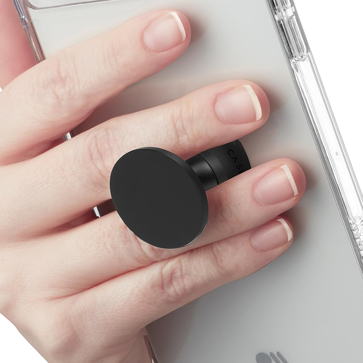 Die Hand einer Person, die ein Telefon mit einem schwarzen Pop-Socket hält, an einer transparenten Handyhülle.