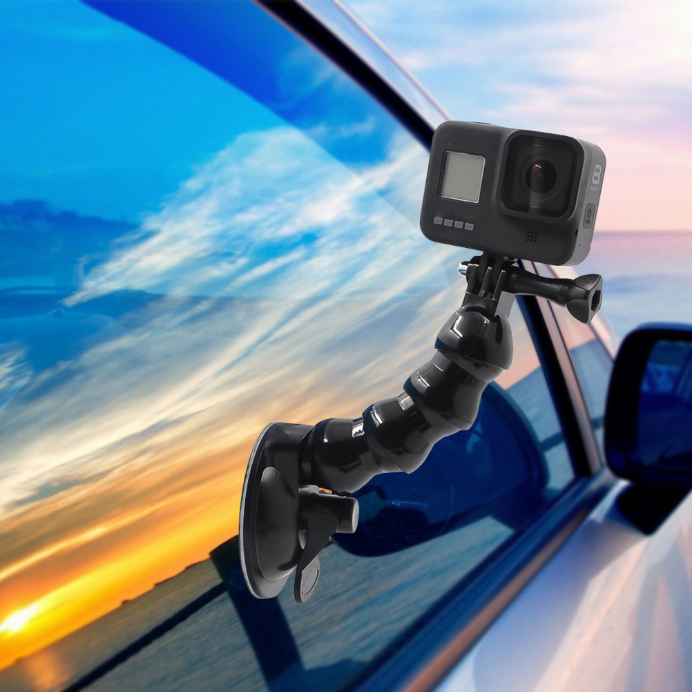 Eine GoPro-Kamera, die mit einer Saugnapfhalterung an einem Autofenster befestigt ist, vor einem Sonnenuntergangshimmel.