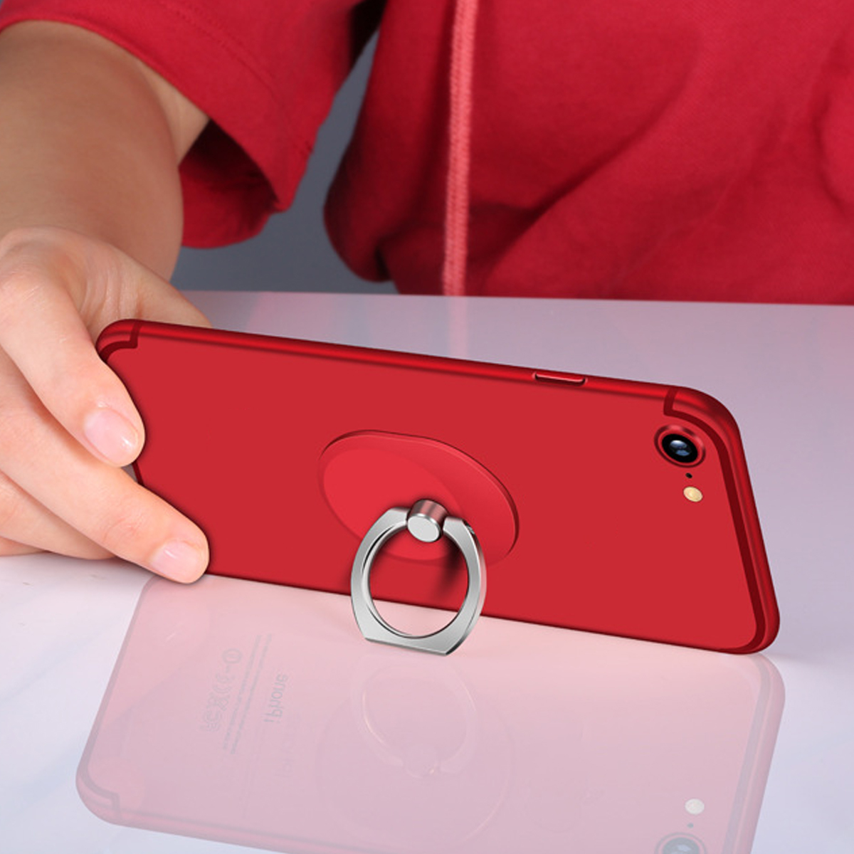 Ein rotes Telefon mit einem silbernen Ringhalter auf der Rückseite. Eine Hand hält das Telefon. Der Ring zeigt nach oben.