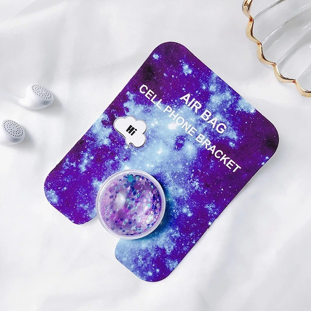 Ein lila Handyhalter im Galaxystil mit Pop-Socket und weißen Ohrhörern.