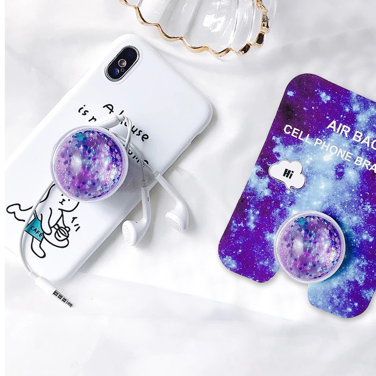 Ein Telefon mit weißer Hülle und einem Pop-Socket. Eine andere Telefonhülle und ein Socket liegen rechts.