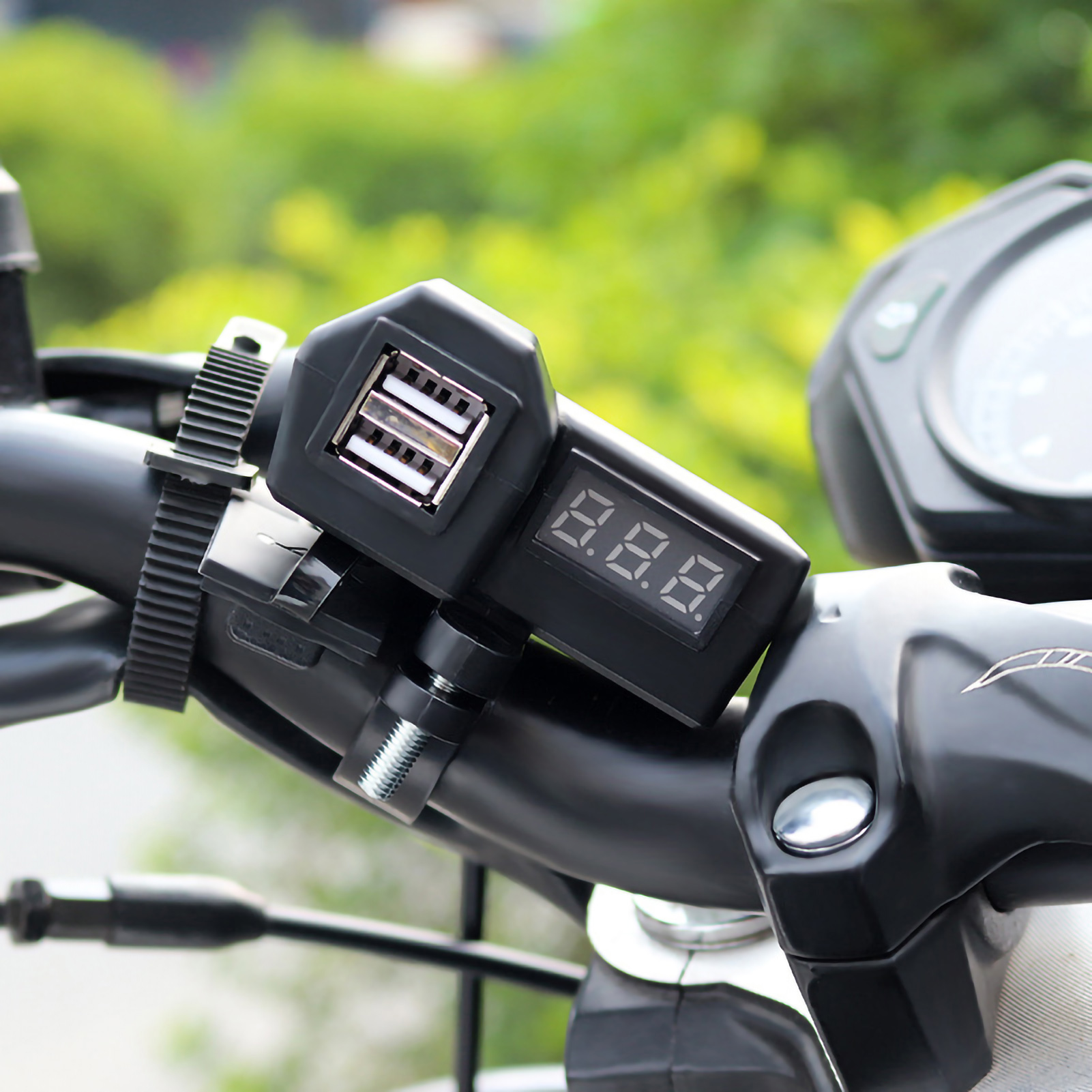Motorradlenker mit USB-Ladegerät und digitaler Spannungsanzeige, unscharfer Hintergrund.