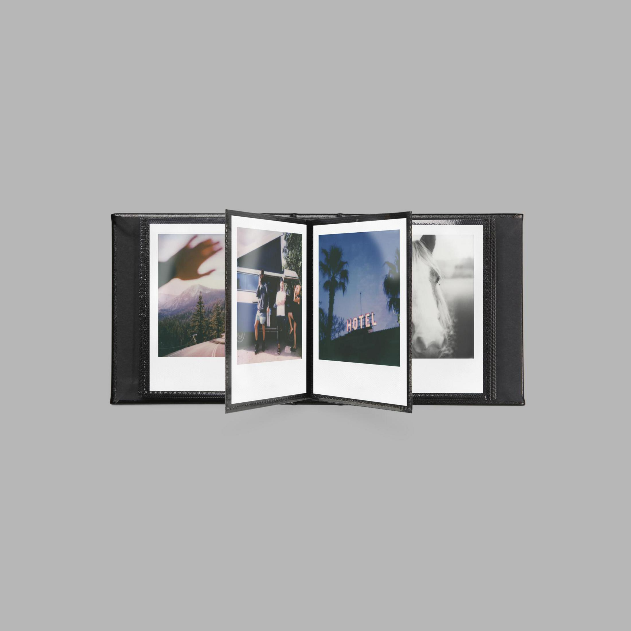 Ein geöffnetes Album mit Polaroid-Fotos; ein Van, ein Hotelschild und ein Pferd.