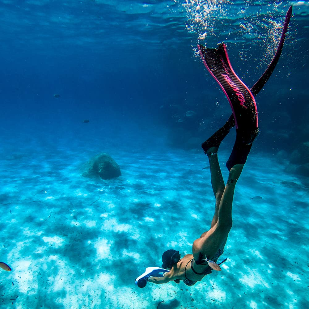 A person snorkeling underwater with fins and a sea scooter.