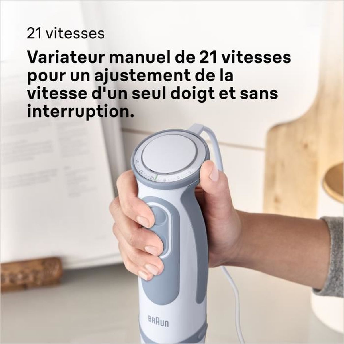 Eine Hand, die ein weiß-graues Braun-Gerät mit Knöpfen und einem Drehregler hält, Text darüber.
