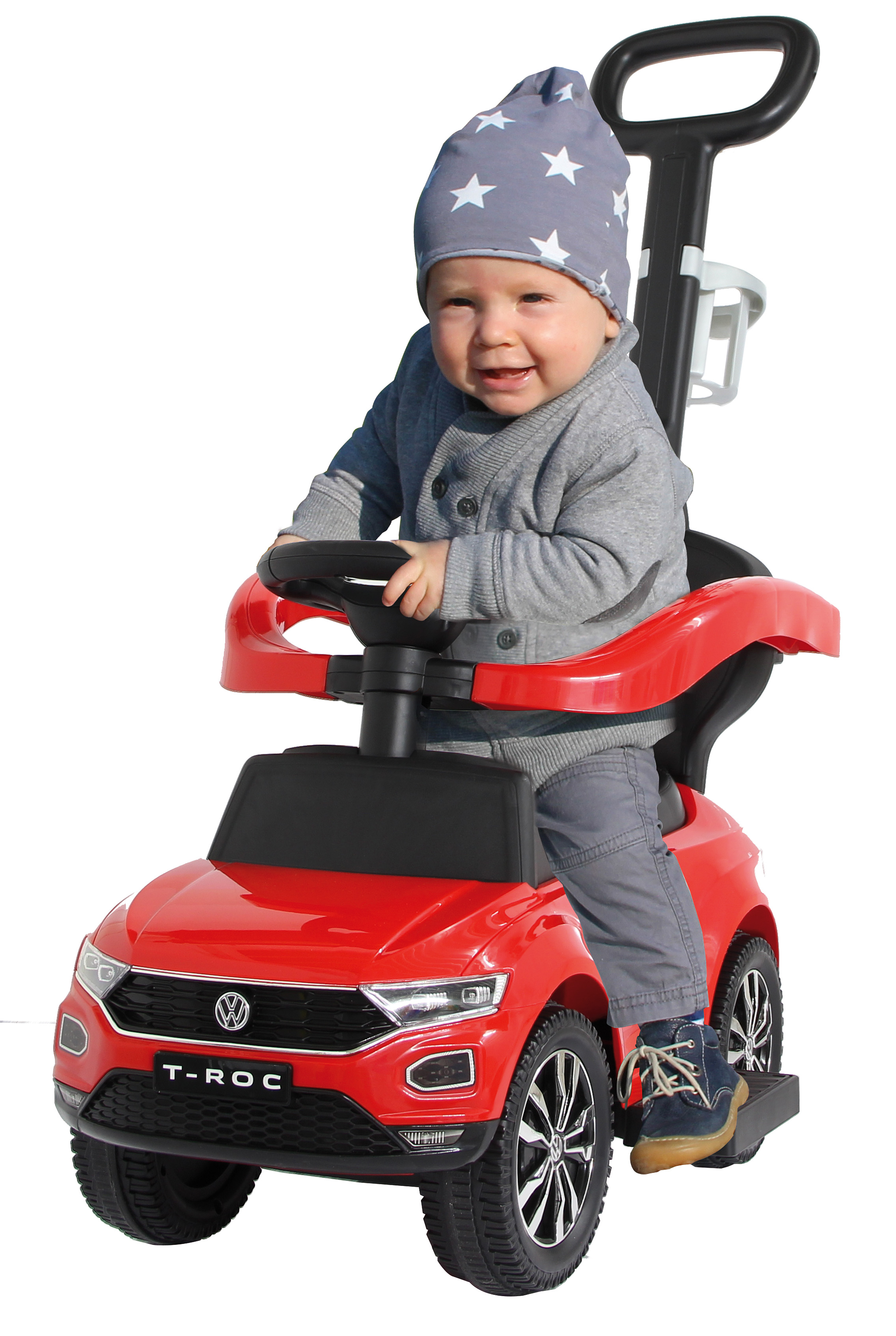 Un niño en un coche de juguete rojo sonriendo, con un gorro gris con estrellas.