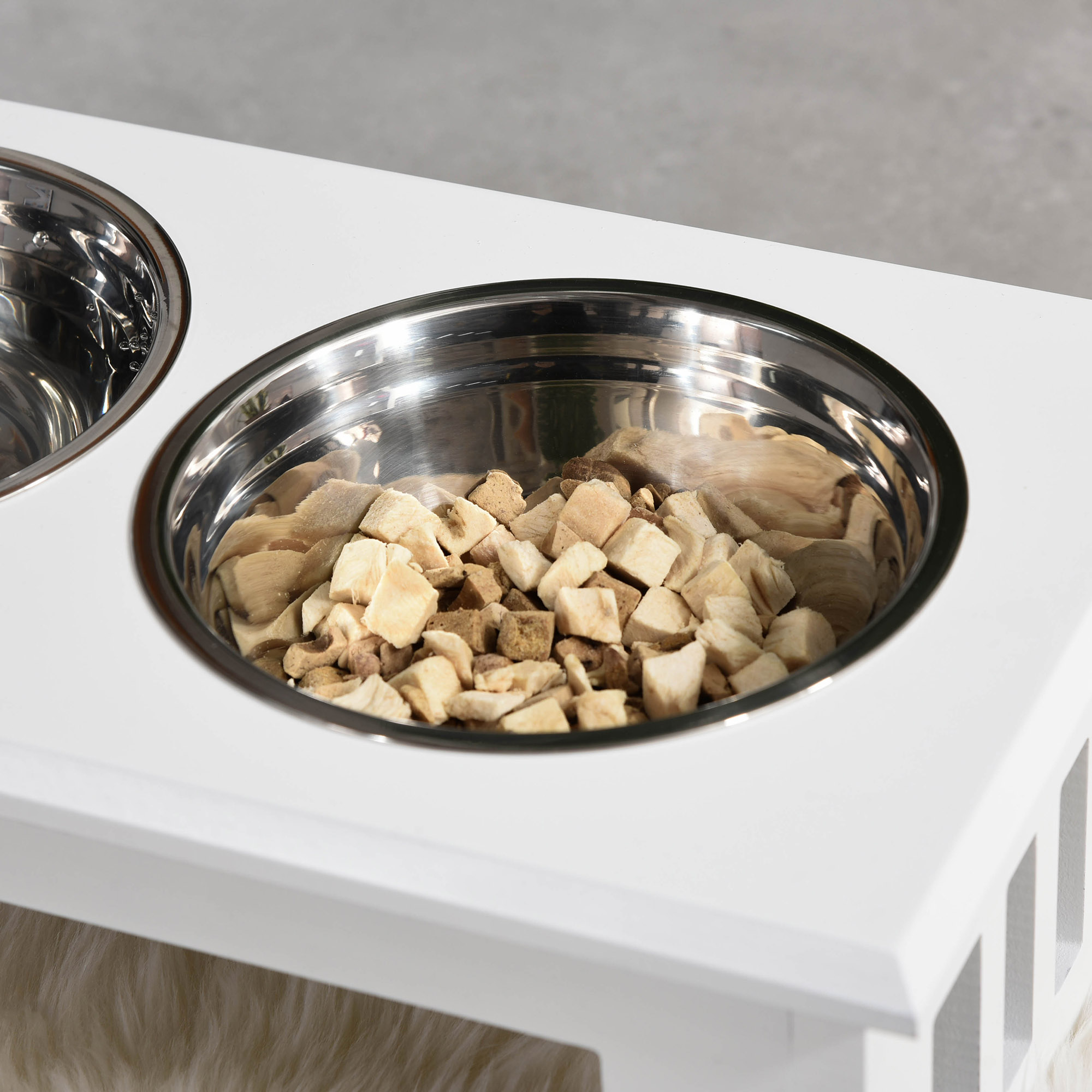 Nahaufnahme von Hundefutter in einer Edelstahlschüssel, die in einem weißen, erhöhten Futterautomaten steht.
