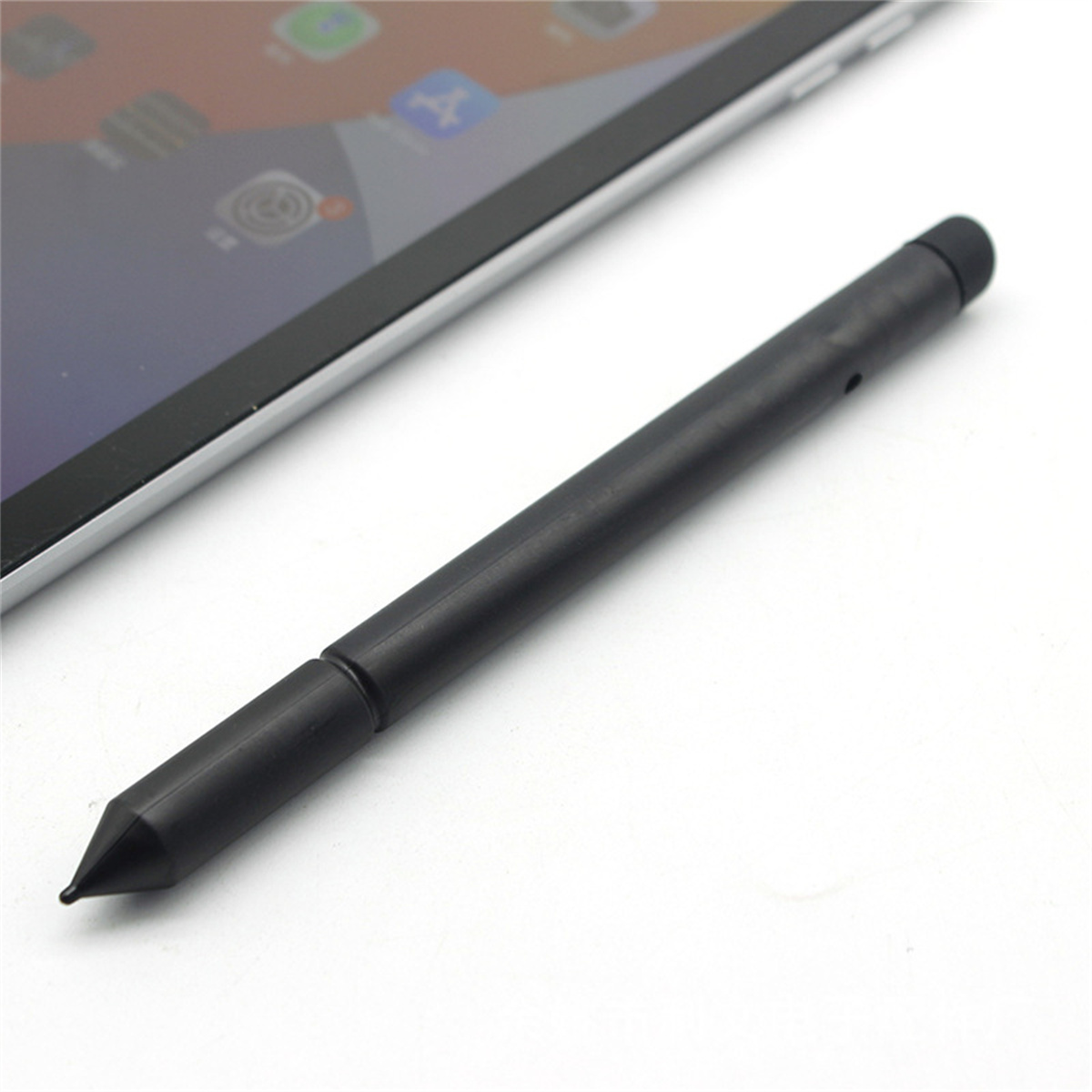 Ein schwarzer Stift liegt neben einem Tablet, wobei die Spitze des Stifts und der Bildschirm des Tablets hervorgehoben werden.