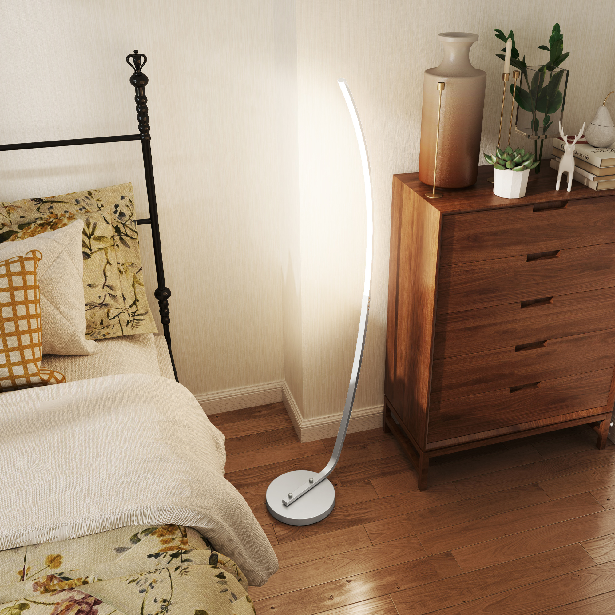 Eine Zimmerecke mit Stehlampe, Holzkommode und Bett mit floraler Bettwäsche. Der Boden ist aus Holz.