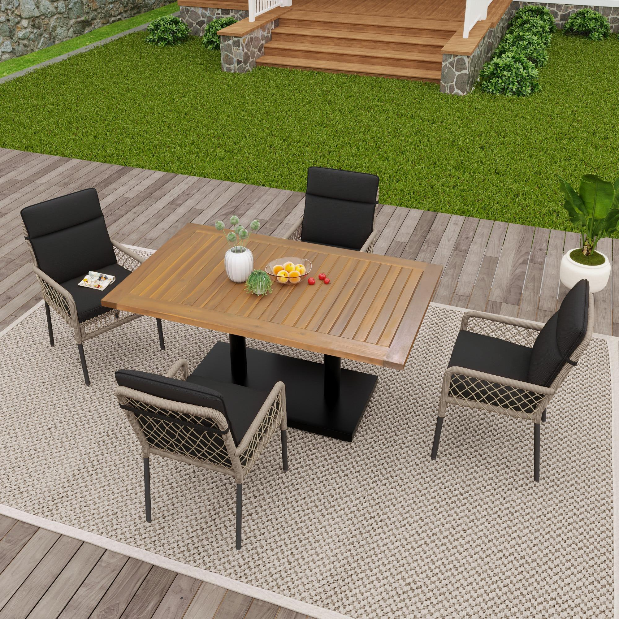 Essgruppe im Freien auf einer Holzterrasse mit Teppich. Blick auf ein Haus.