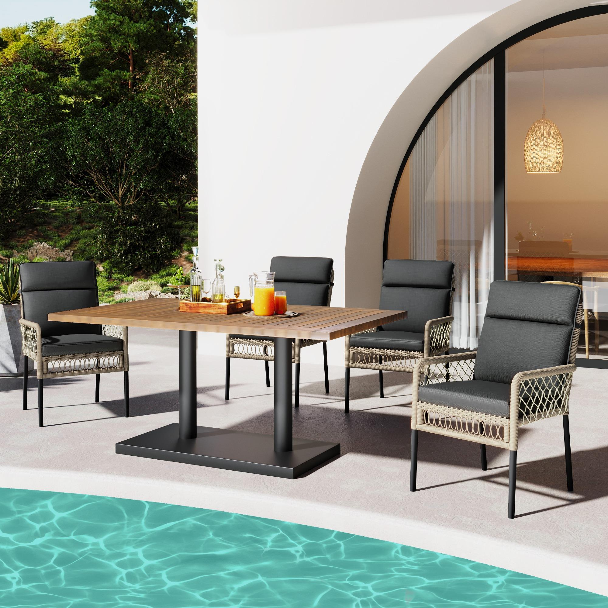 Essgruppe im Freien mit Holztisch und vier Stühlen mit schwarzen Kissen, in der Nähe eines Pools.