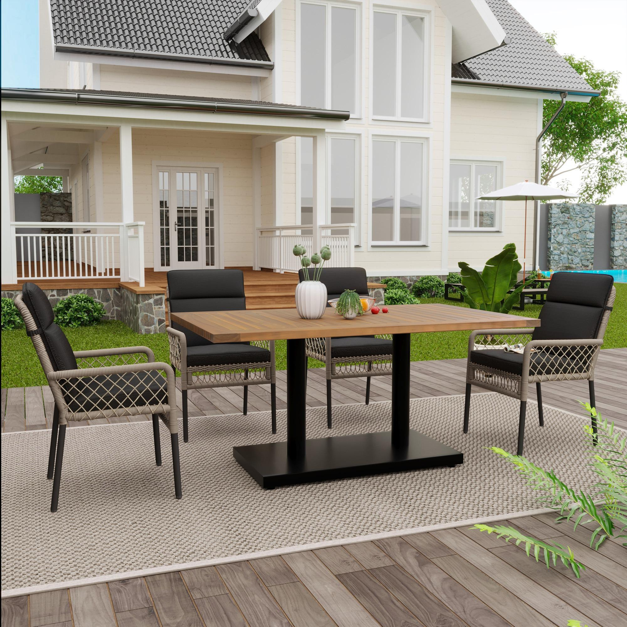 Essgruppe im Freien mit Holztisch, vier Stühlen und einem Haus im Hintergrund. Ein Teppich auf einem Holzdeck.