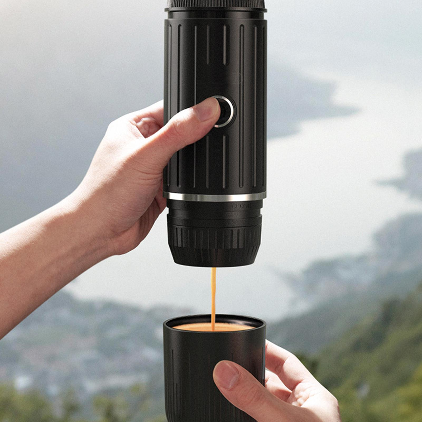 Eine Hand gießt Kaffee aus einem schwarzen tragbaren Kaffeezubereiter in eine schwarze Tasse, vor verschwommenem Hintergrund.