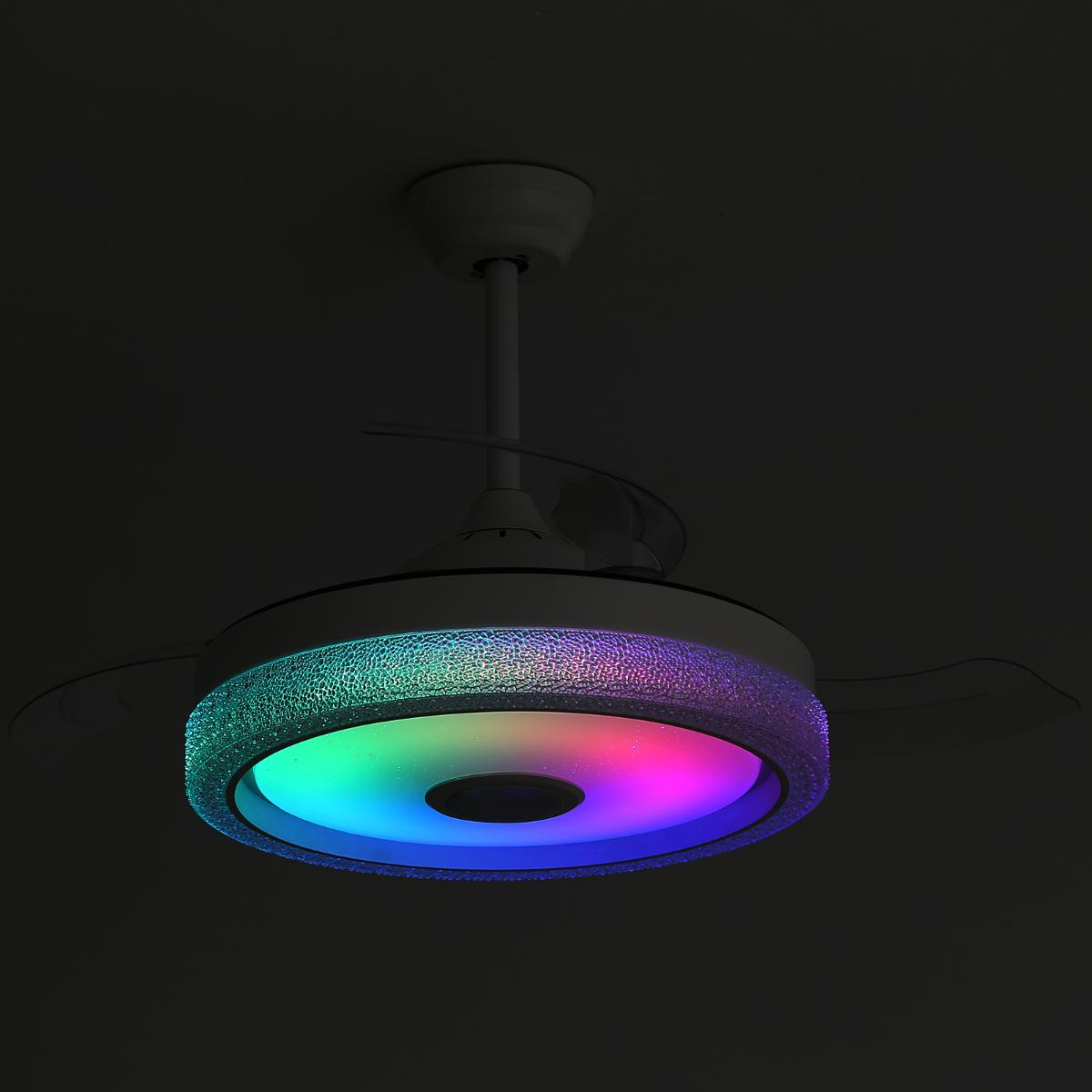 Ein weißer Deckenventilator mit mehrfarbigem Licht. Dunkler Hintergrund.