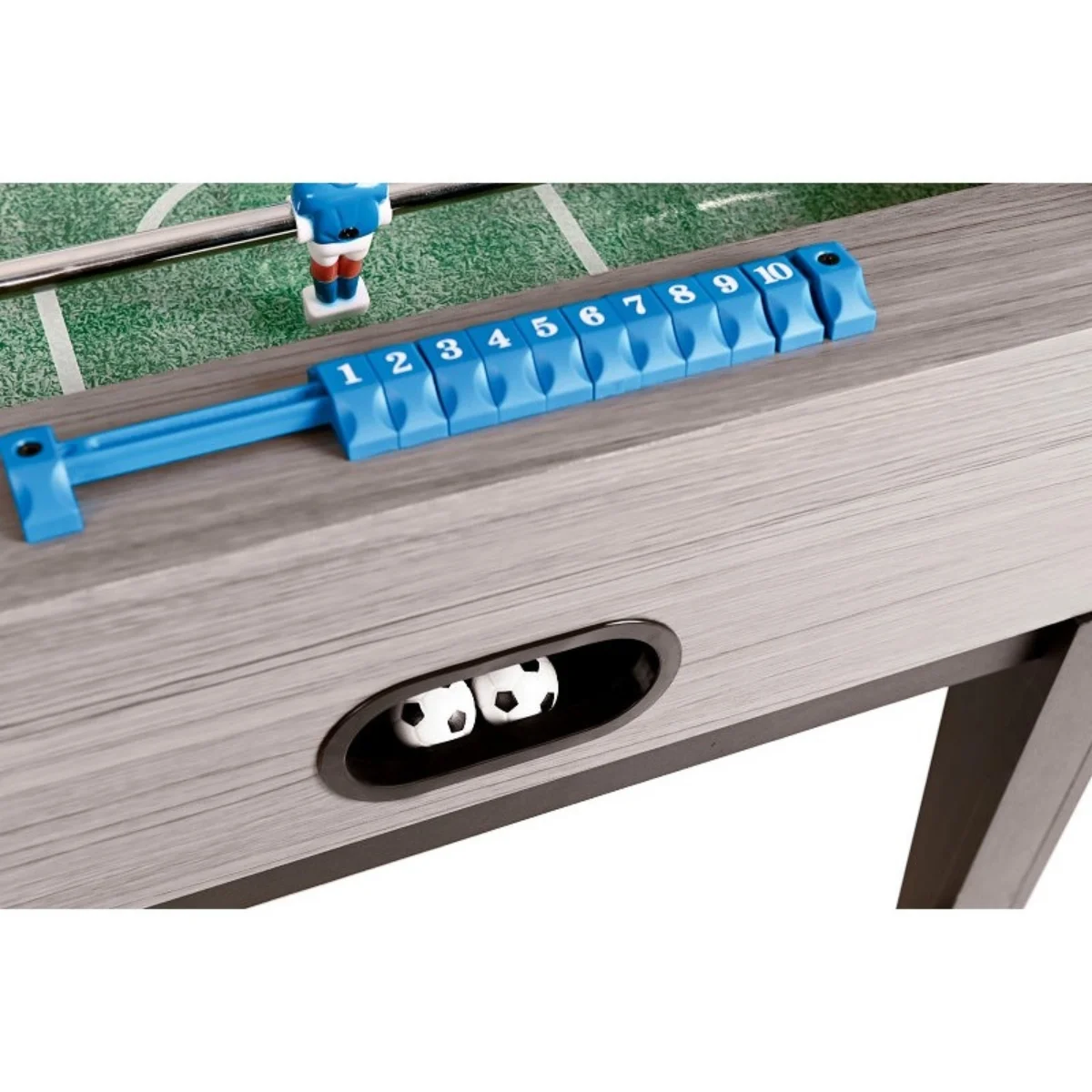 Foosball table detail. Blue score keeper, two soccer balls and a few player figures. Grey wooden frame.