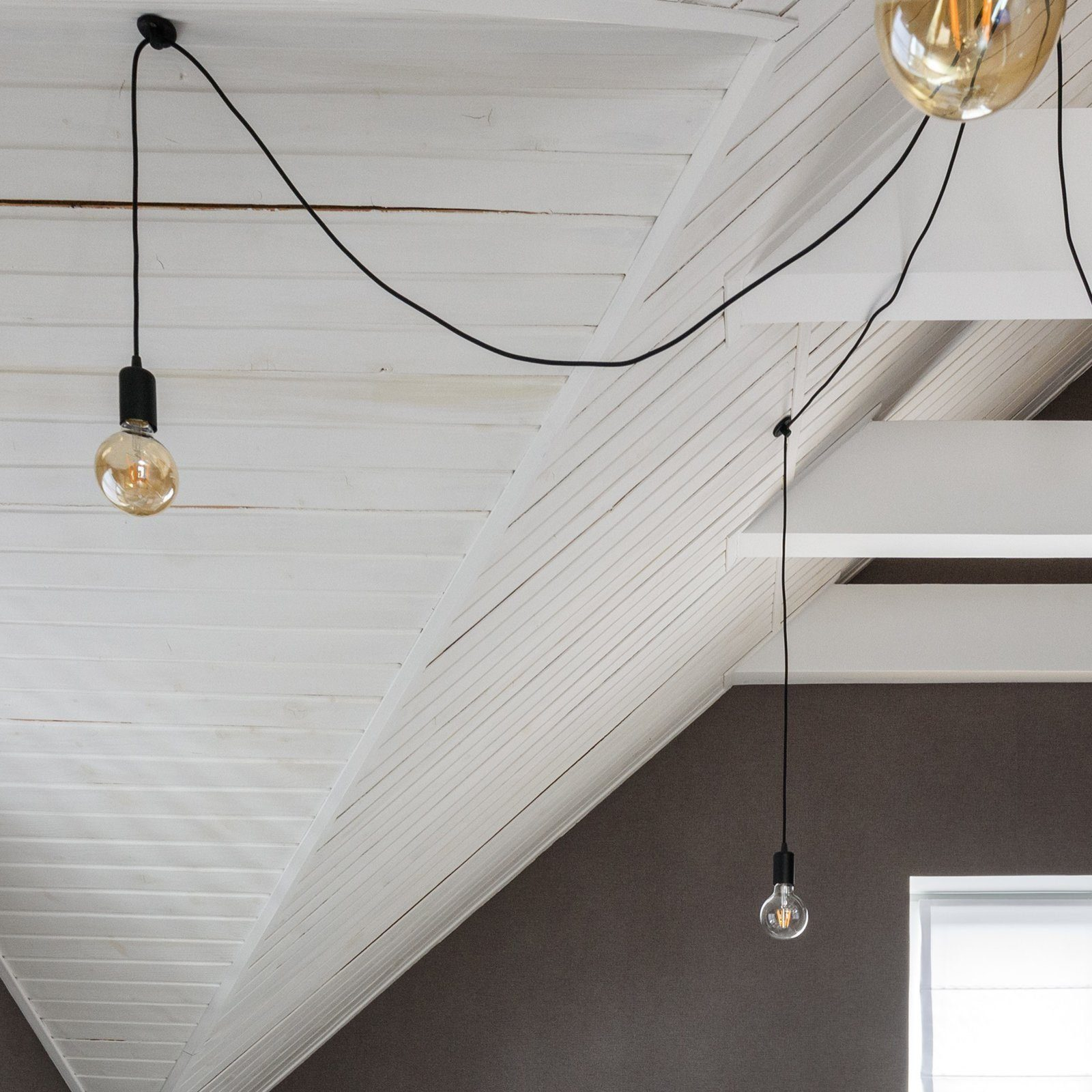 Trzy lampy wiszące zwisające z białego drewnianego sufitu. Każda lampa ma żarówkę.