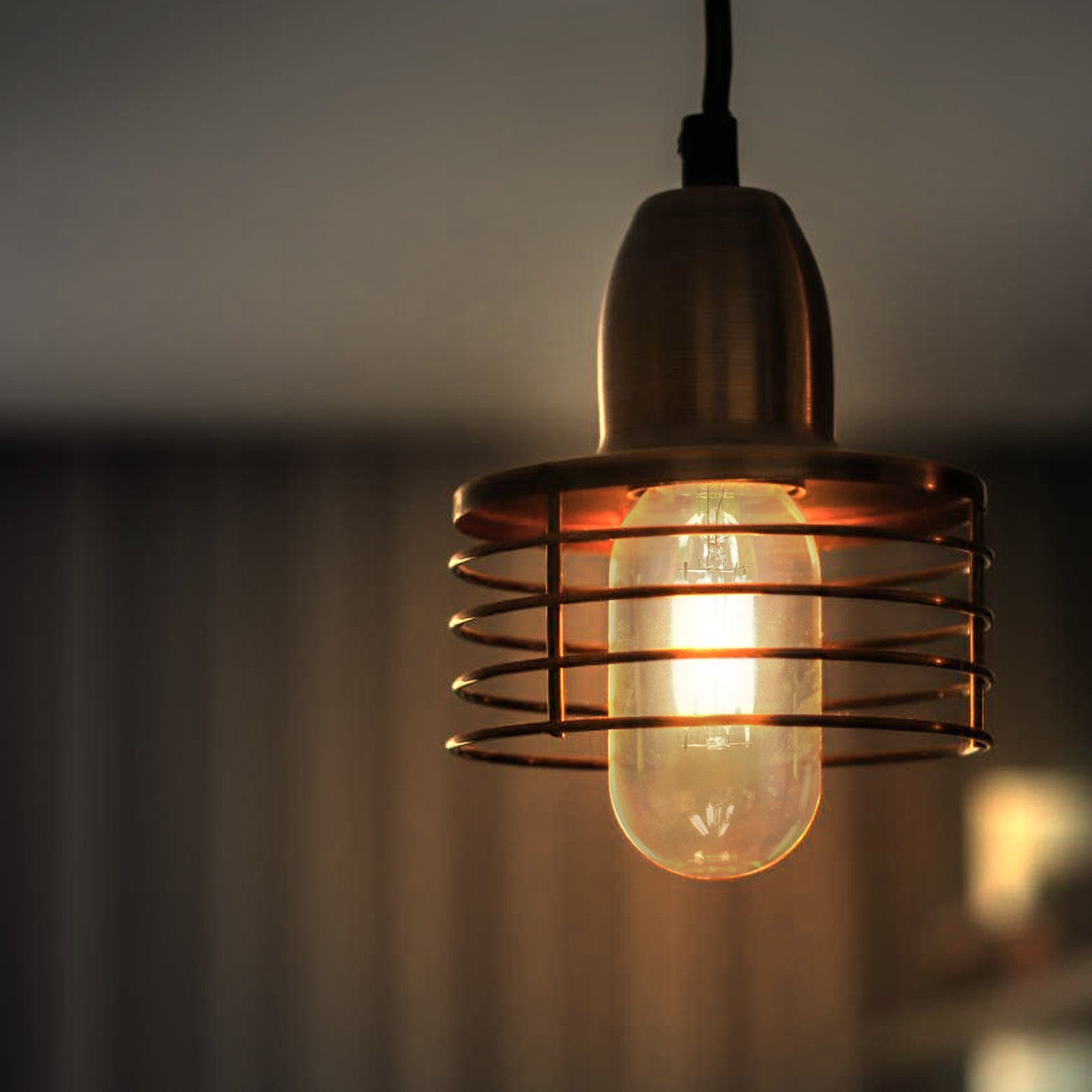 Świecąca żarówka w metalowej klatce, zwisająca z sufitu. Tło jest rozmyte.