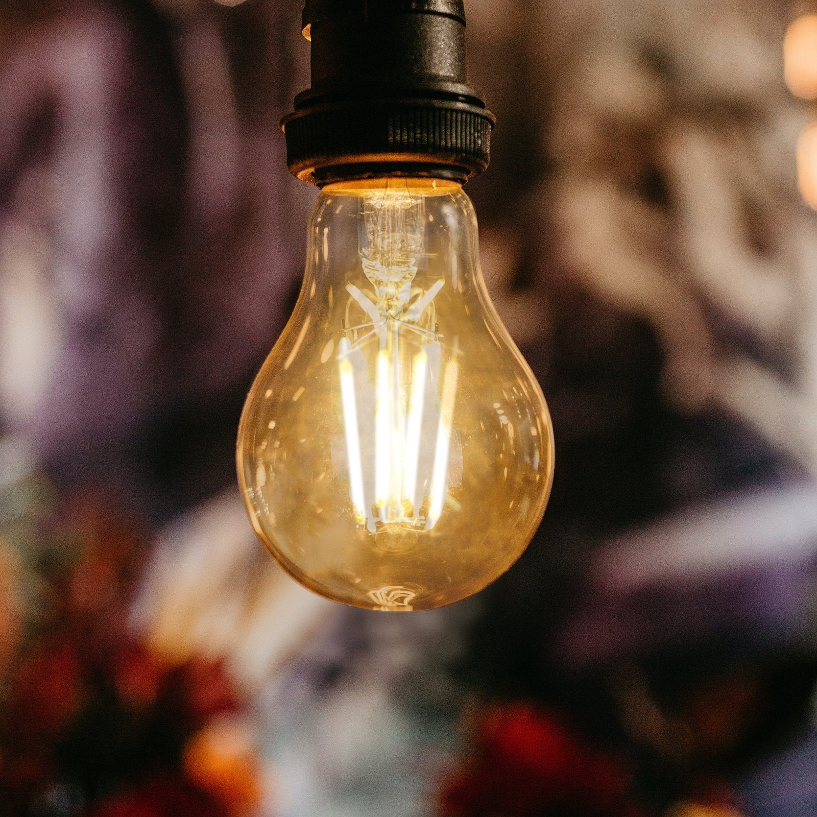 Zbliżenie na żarówkę. Żarówka jest z przezroczystego szkła z żółtym włóknem.