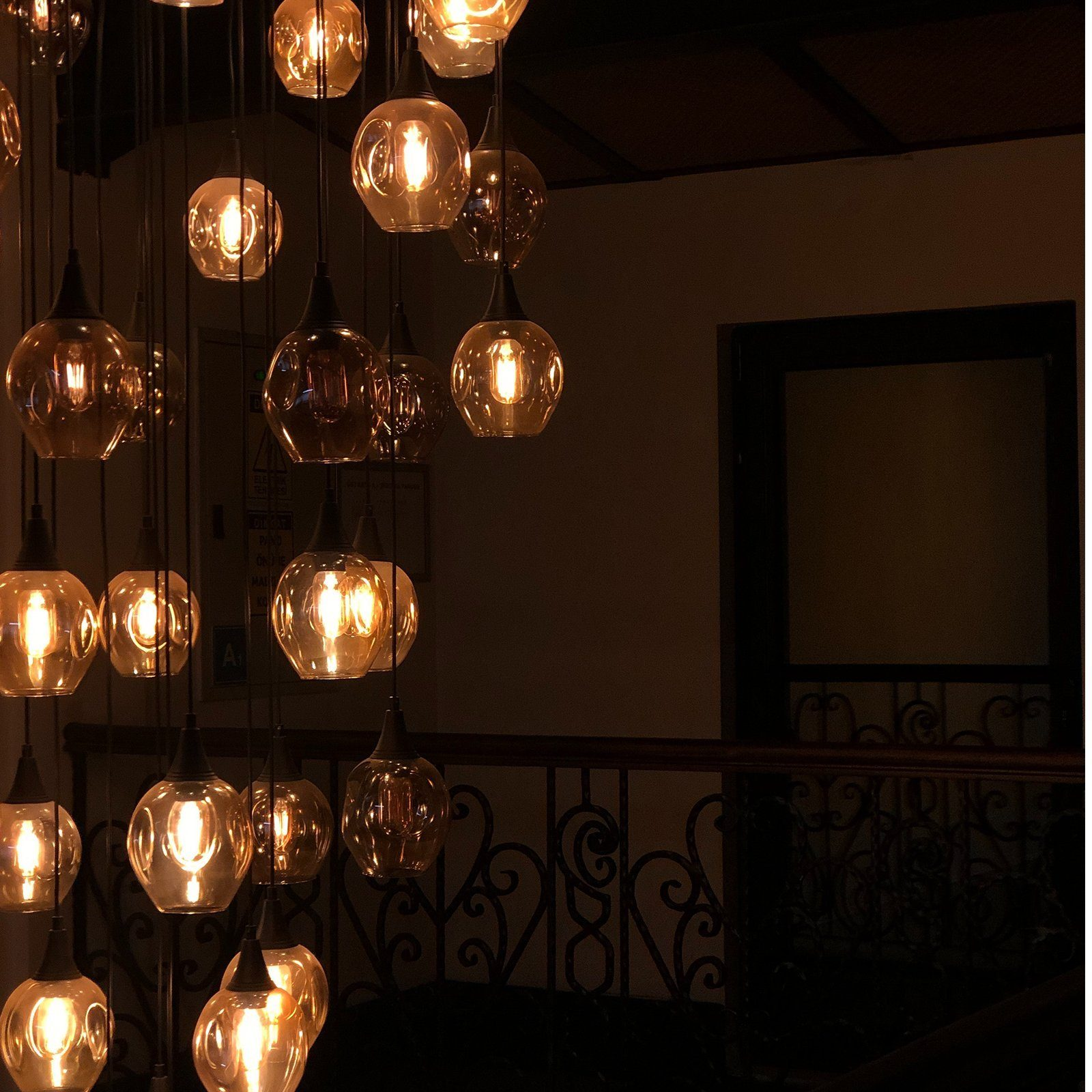 Ciemny pokój z wieloma wiszącymi światłami, każde z ciepłym blaskiem, tworząc przytulną atmosferę.