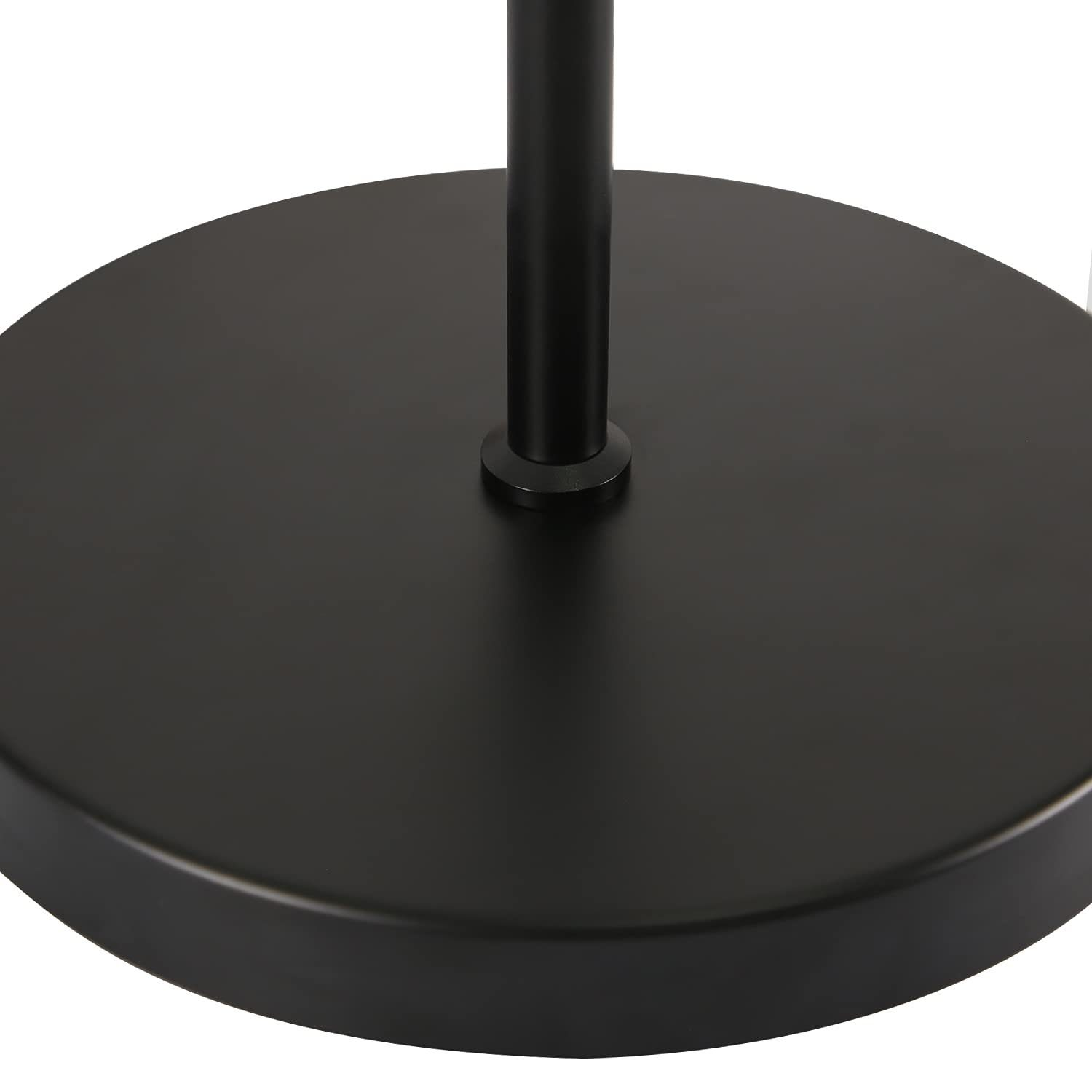 Zbliżenie na czarną, metalową, okrągłą podstawę lampy stojącej, pokazującą jej płaską powierzchnię.