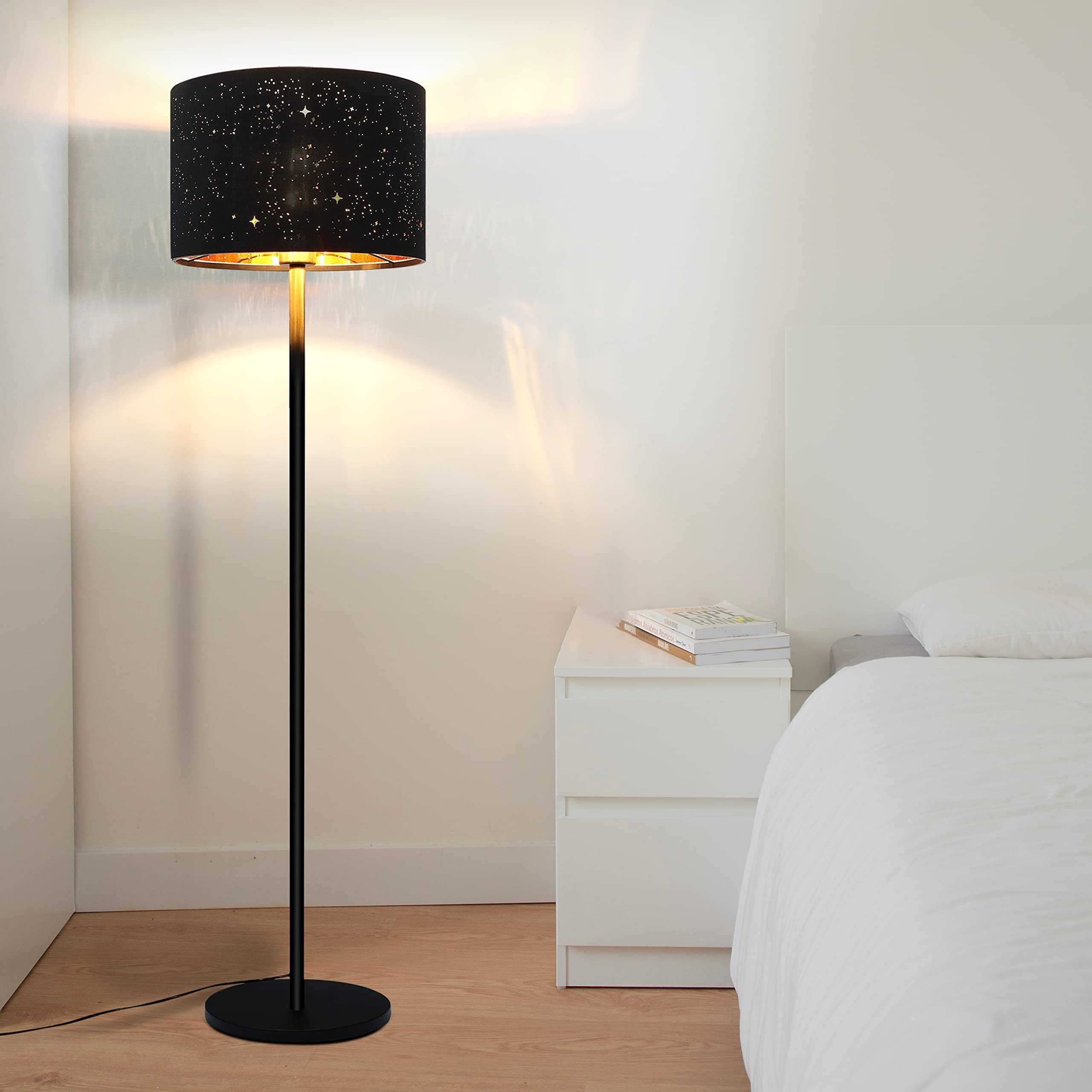 Una lampada da terra con un paralume a stelle si trova accanto a un letto e a un comodino.
