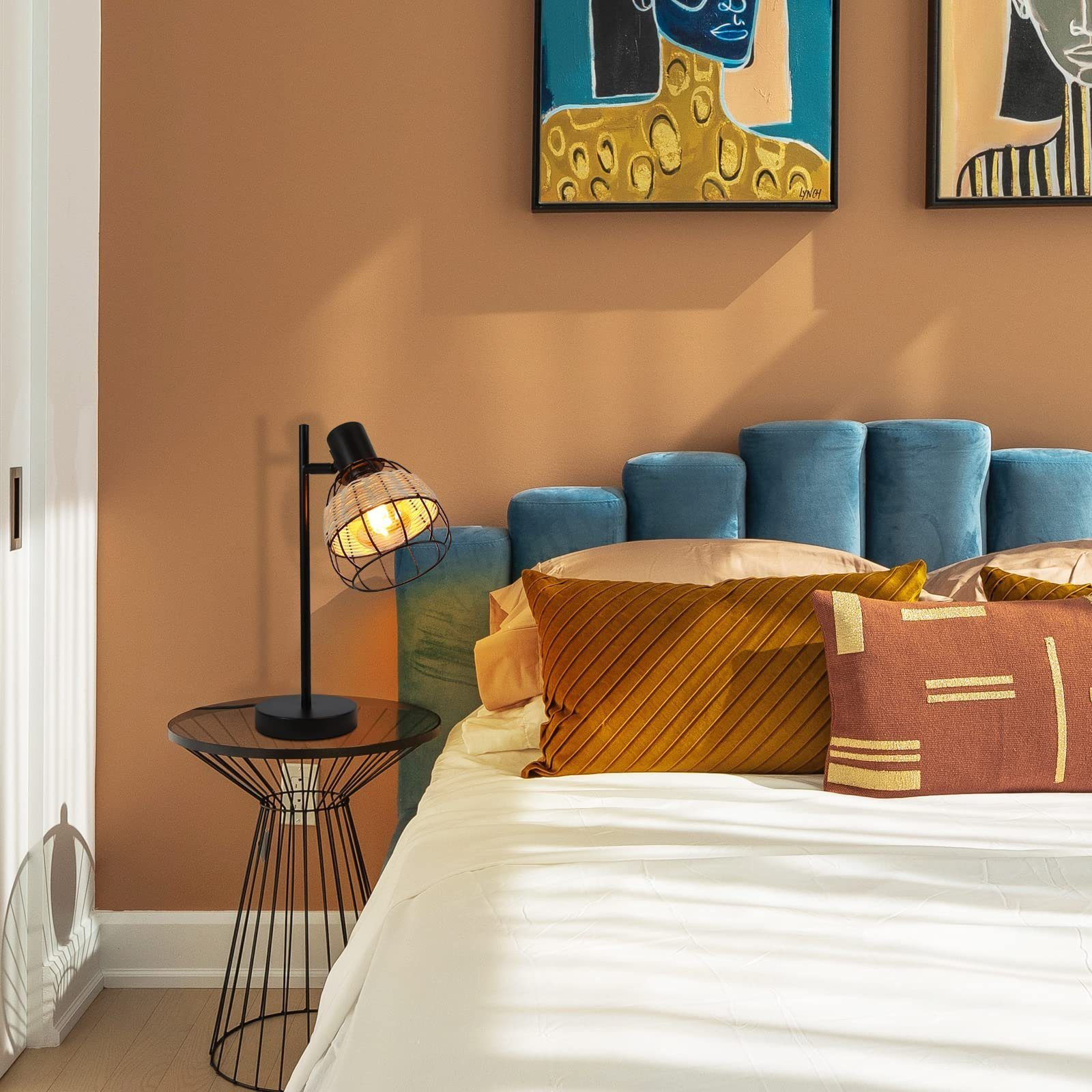 Czarna lampa z tkanym abażurem stoi na stole. Łóżko i poduszki są w tle.