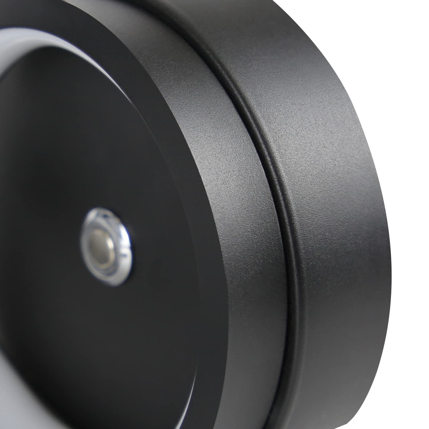 Zbliżenie czarnej, okrągłej podstawy lampy, pokazujące szczegóły powierzchni.