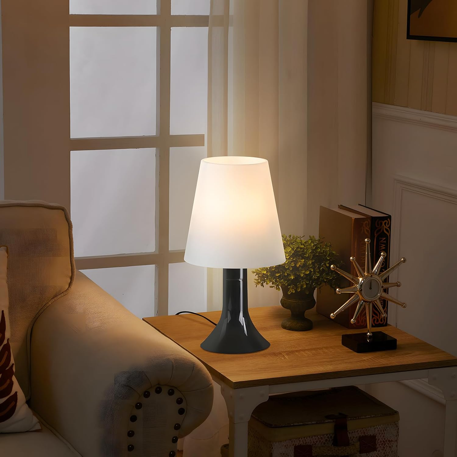 Lampa na stole obok sofy, z książką i dekoracjami.