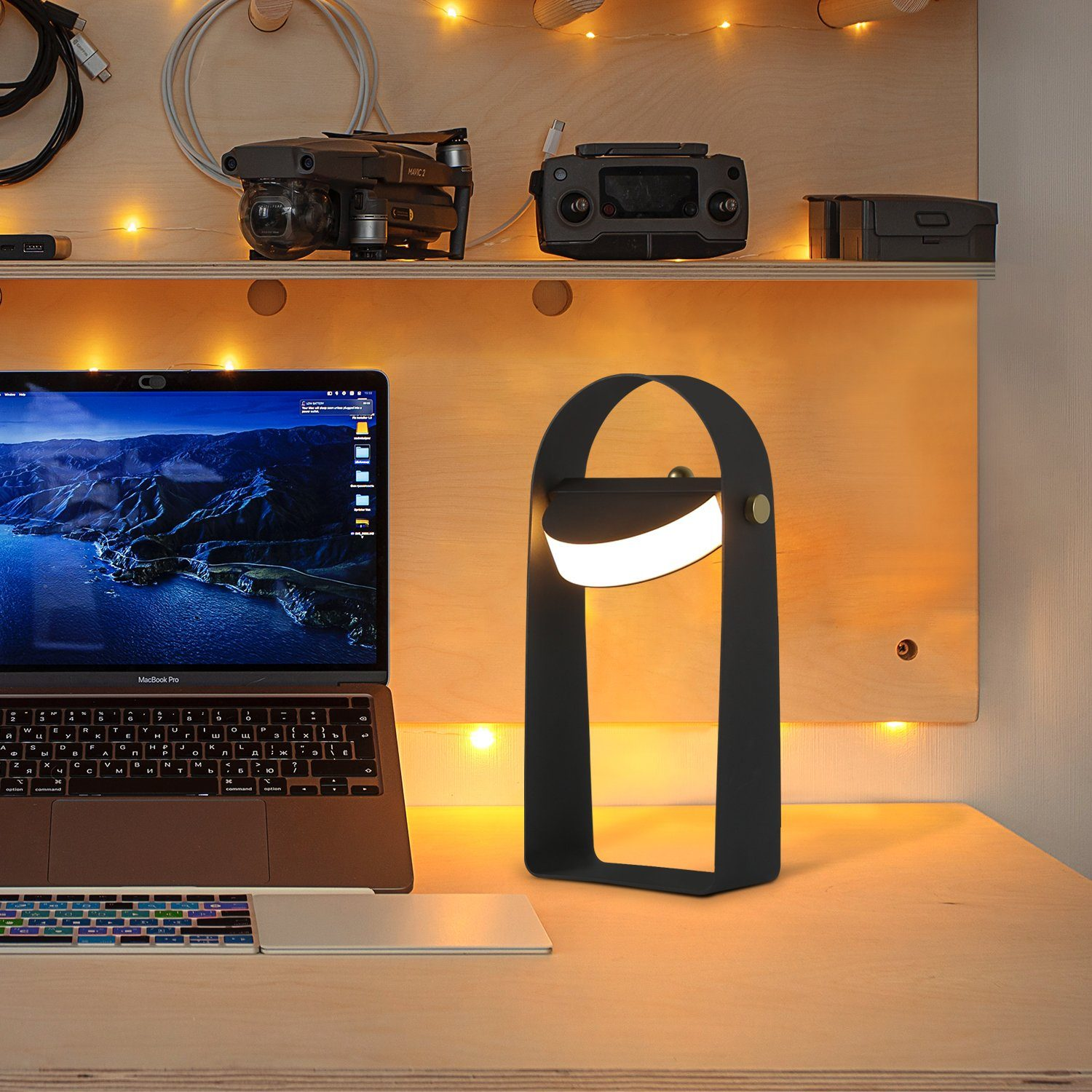 Czarna lampa z białym światłem, umieszczona na biurku z laptopem, akcesoriami i drewnianą ścianą.