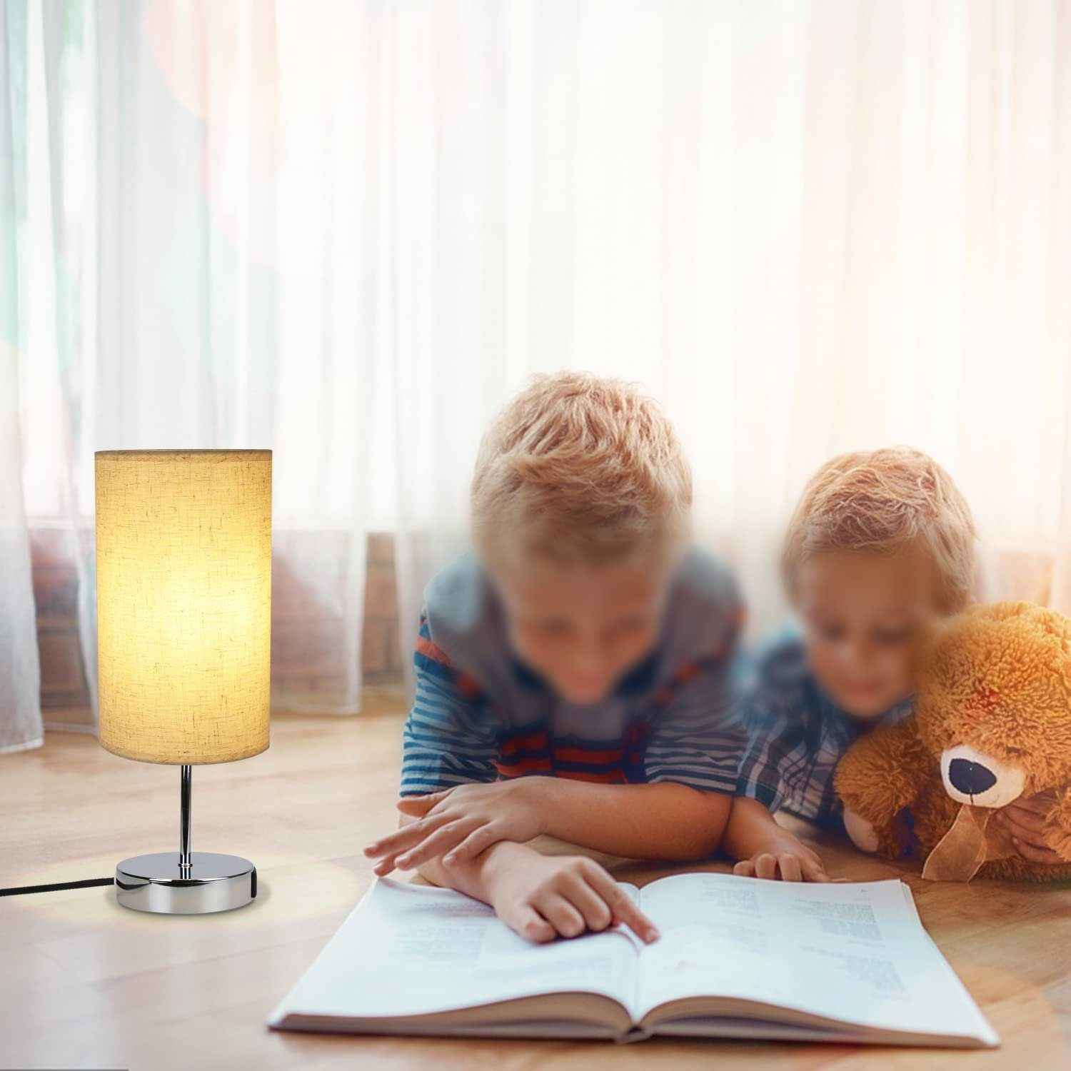 Zapalona lampa na podłodze. Dwoje dzieci czyta książkę, a obok jest pluszowy miś.