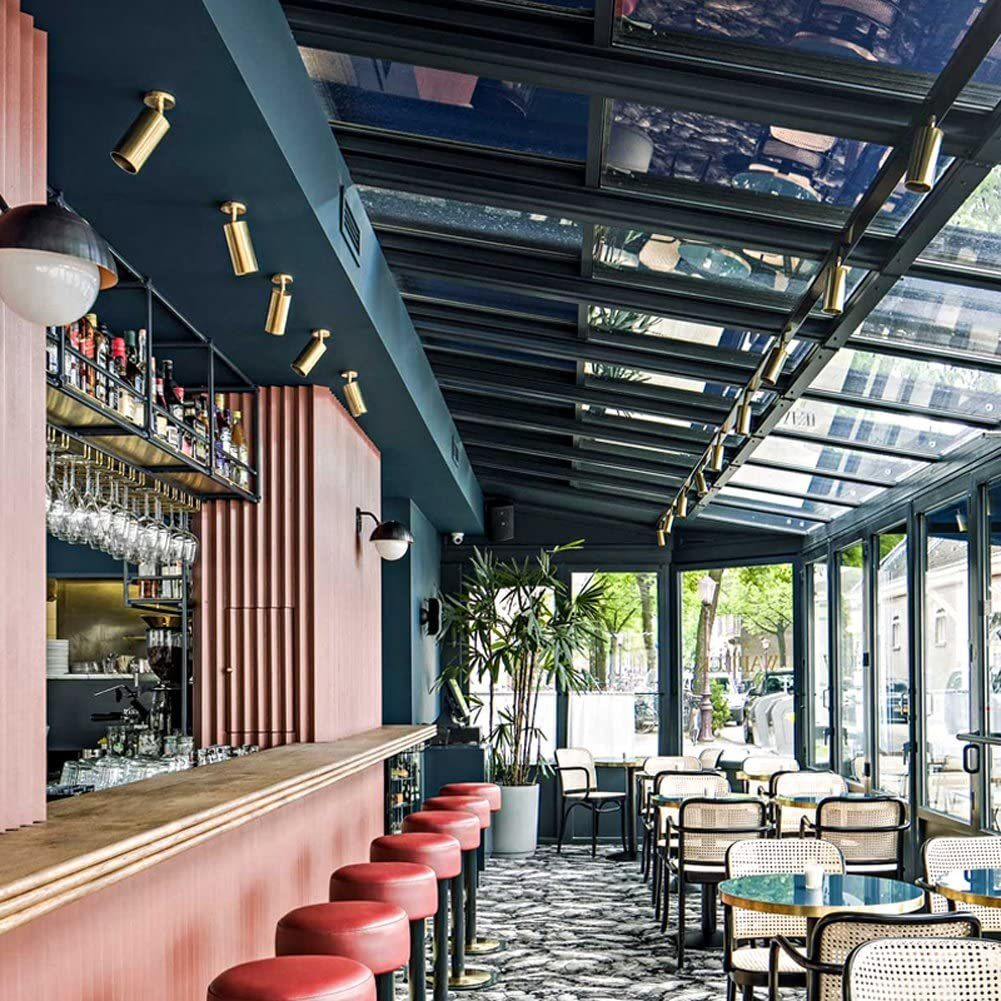 Interno di un bar moderno con sgabelli rossi e soffitto in vetro.