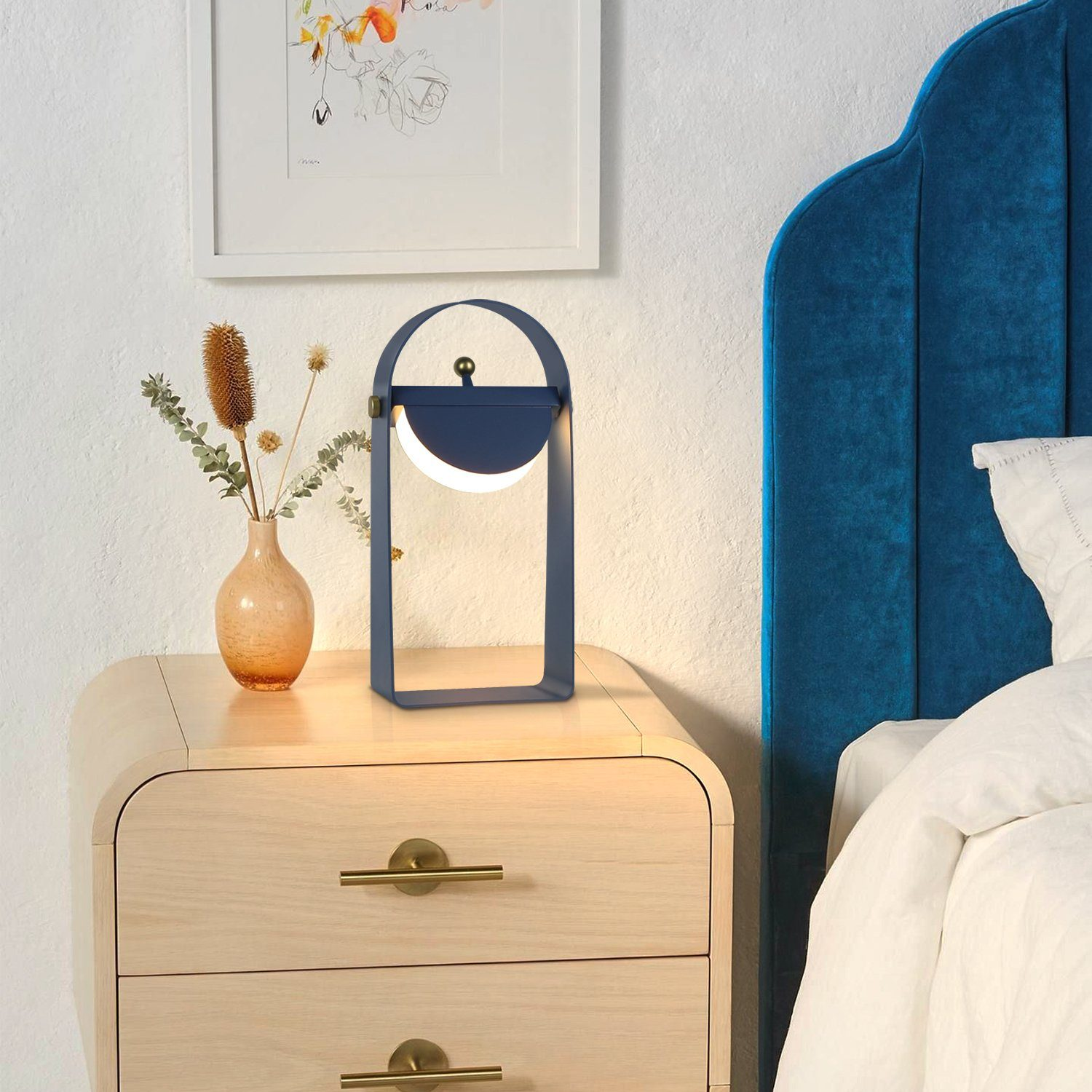 Niebiesko-biała lampa stoi na drewnianej szafce nocnej. W pobliżu są kwiaty.