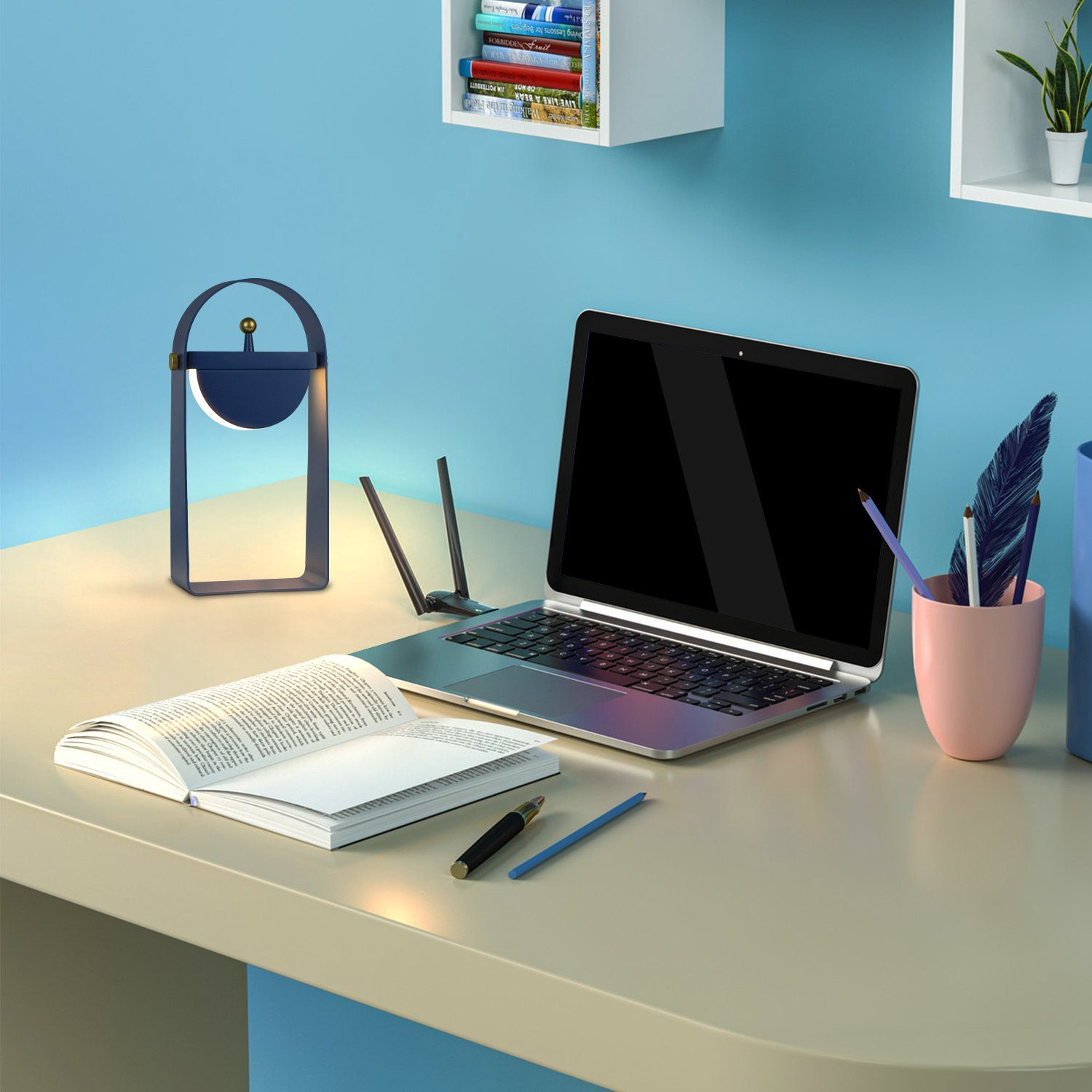 Biurko z laptopem, lampą, książkami i akcesoriami na tle niebieskiej ściany.