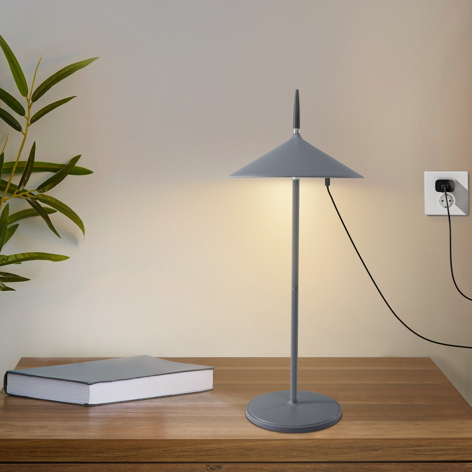 Szara lampa na drewnianym stole. W pobliżu roślina i gniazdko.