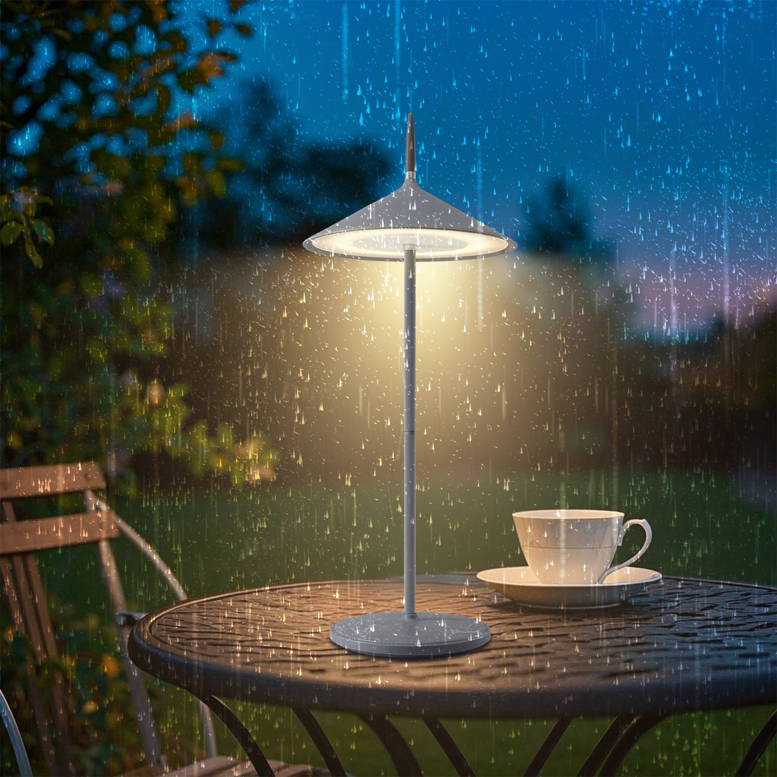 Lampa na stole na zewnątrz w deszczu. Na stole filiżanka ze spodkiem.