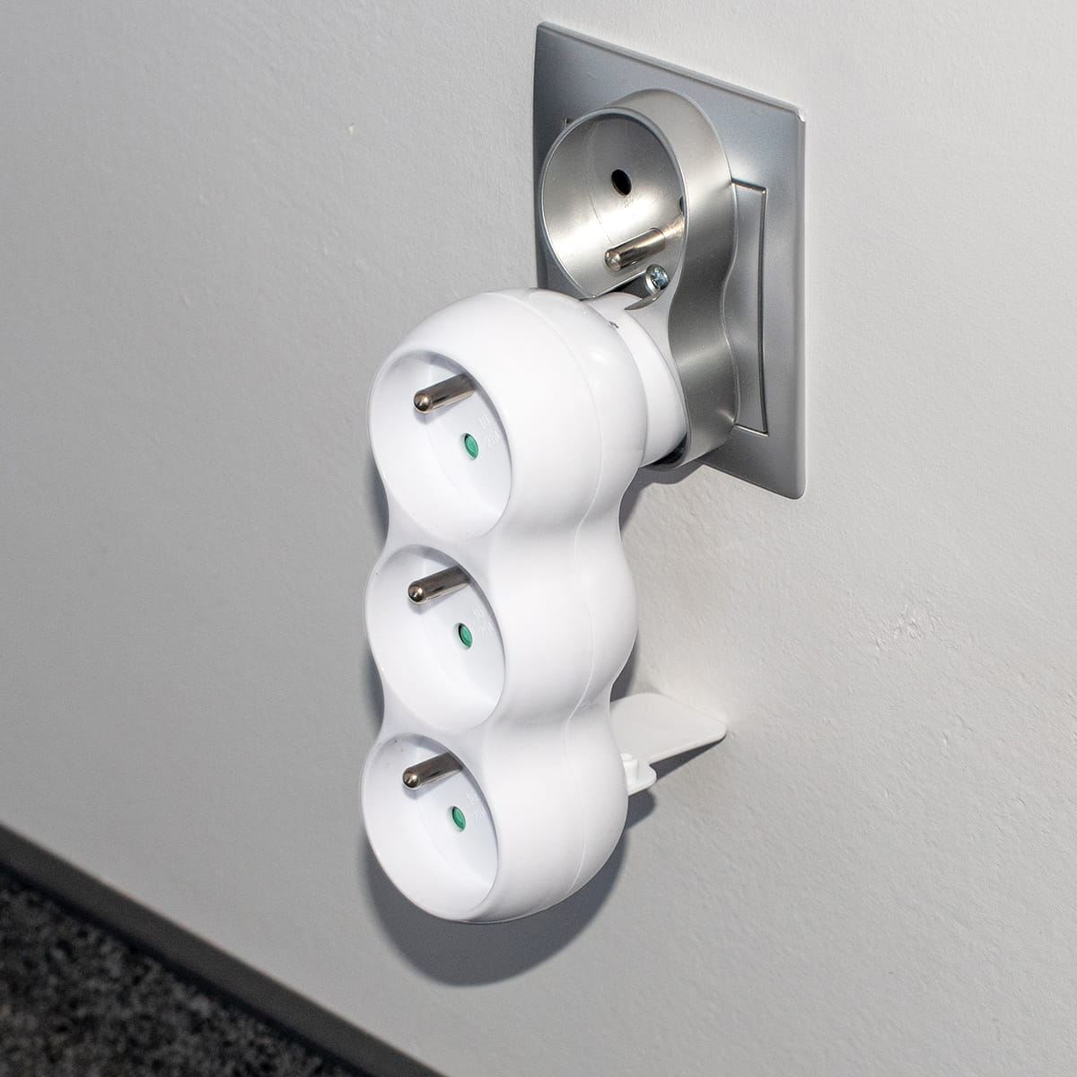 Biały, trójgniazdowy adapter wpięty do gniazdka ściennego. Widok z góry.