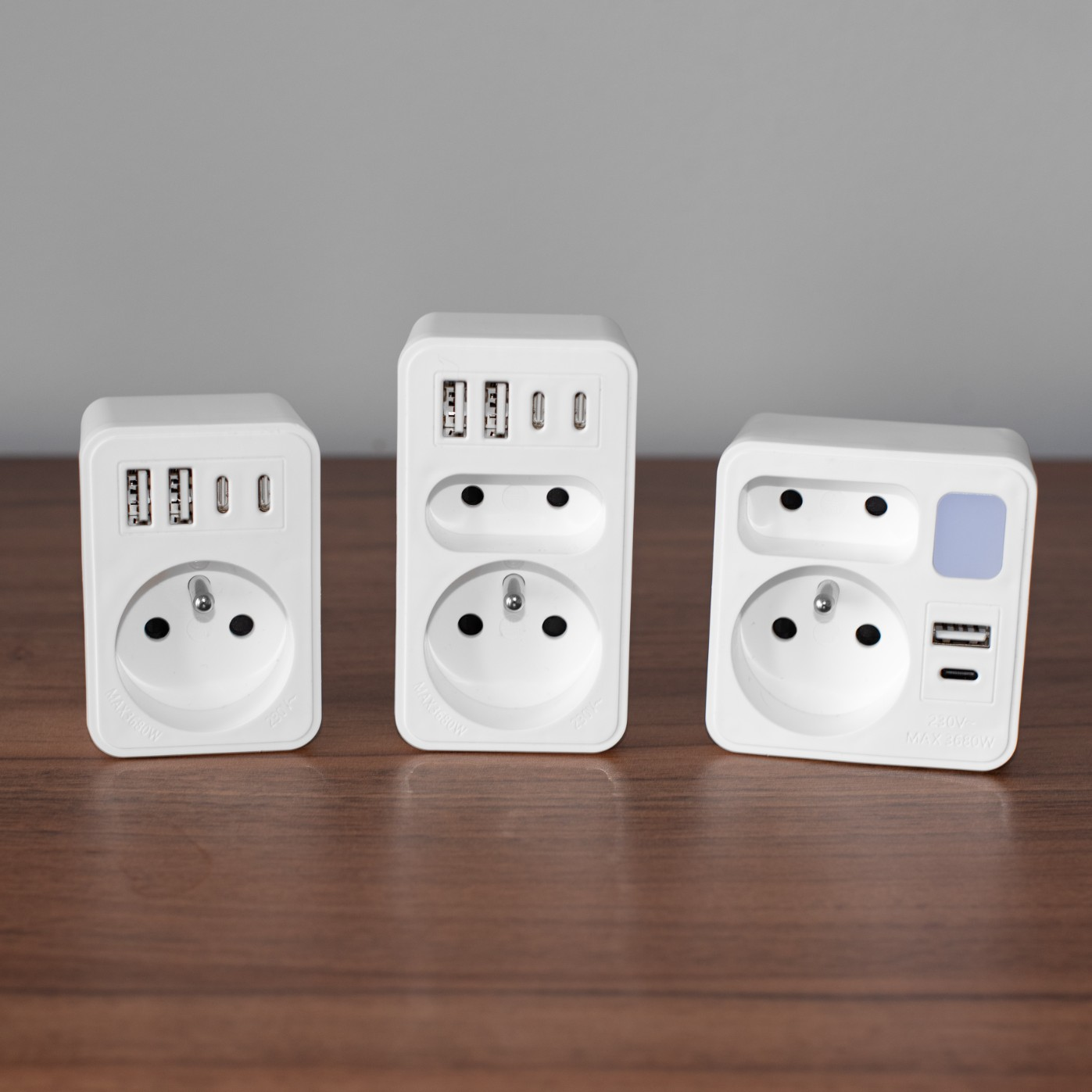 Trzy białe adaptery na drewnianej powierzchni, z portami USB.