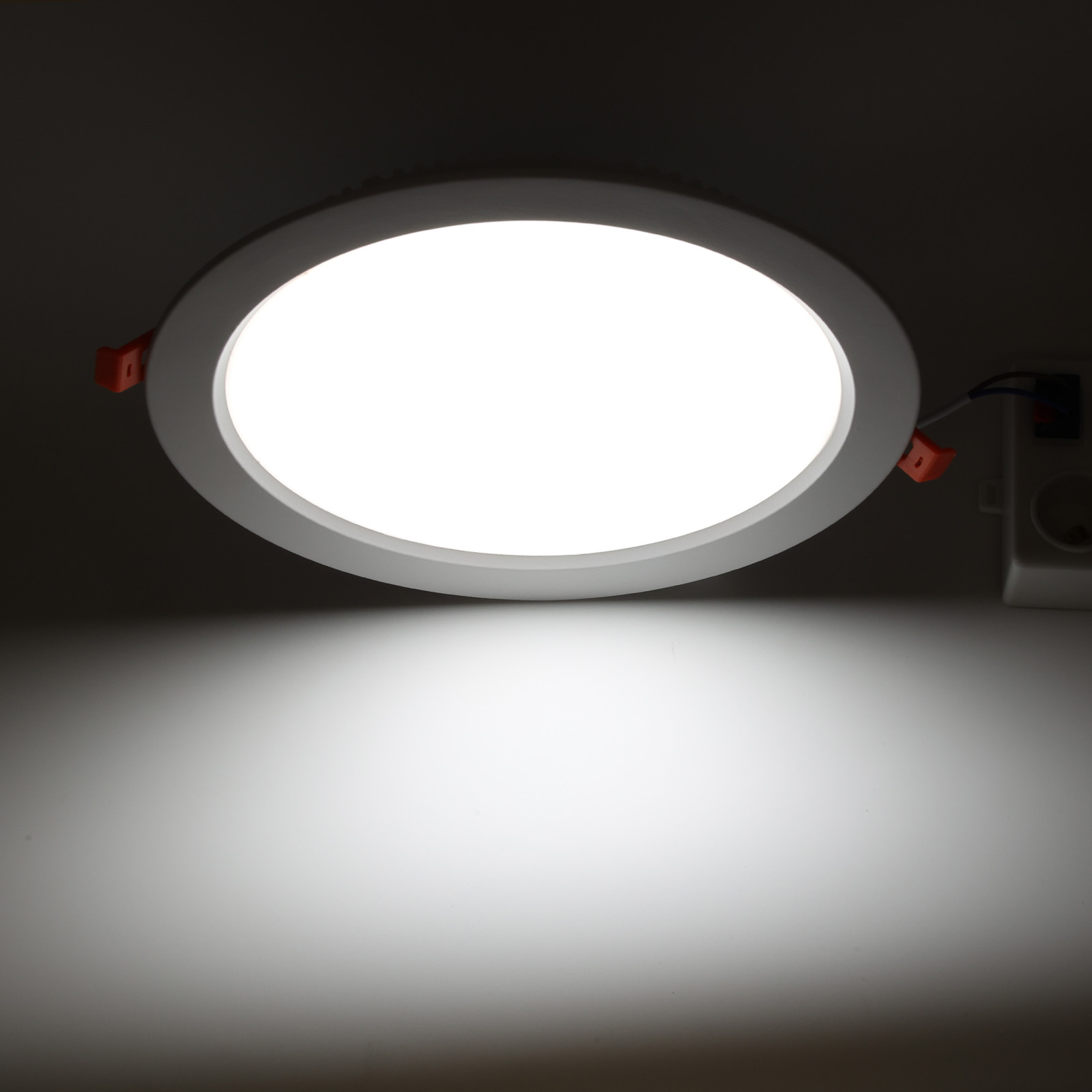 Luz de techo LED blanca emitiendo una luz blanca brillante. Proyecta un círculo de luz sobre un fondo oscuro.