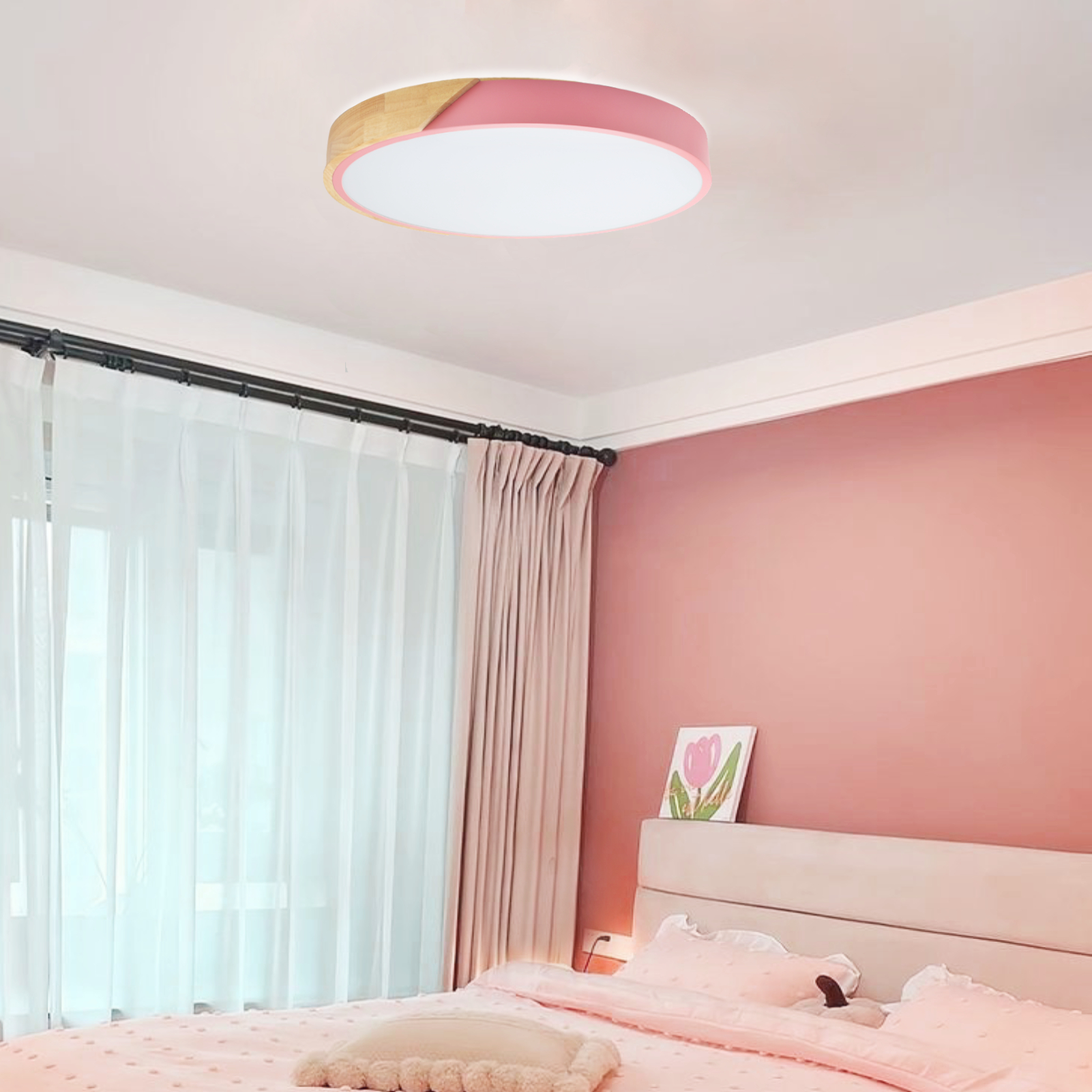 Una luz de techo con molduras rosas en un dormitorio. Hay una cama, cortinas y una pintura.