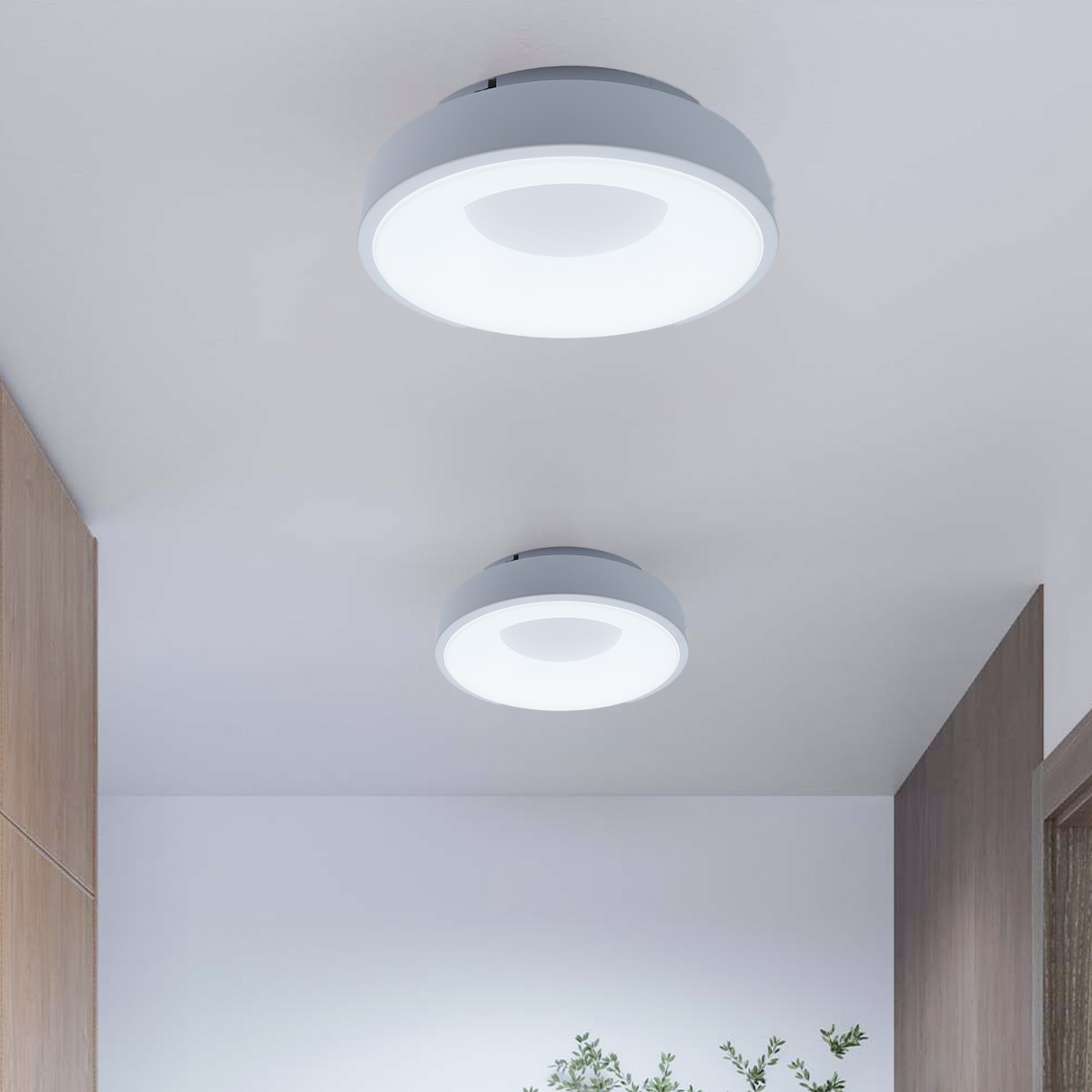Dos luces de techo están instaladas en un pasillo. Las luces son redondas y blancas, con un borde gris.