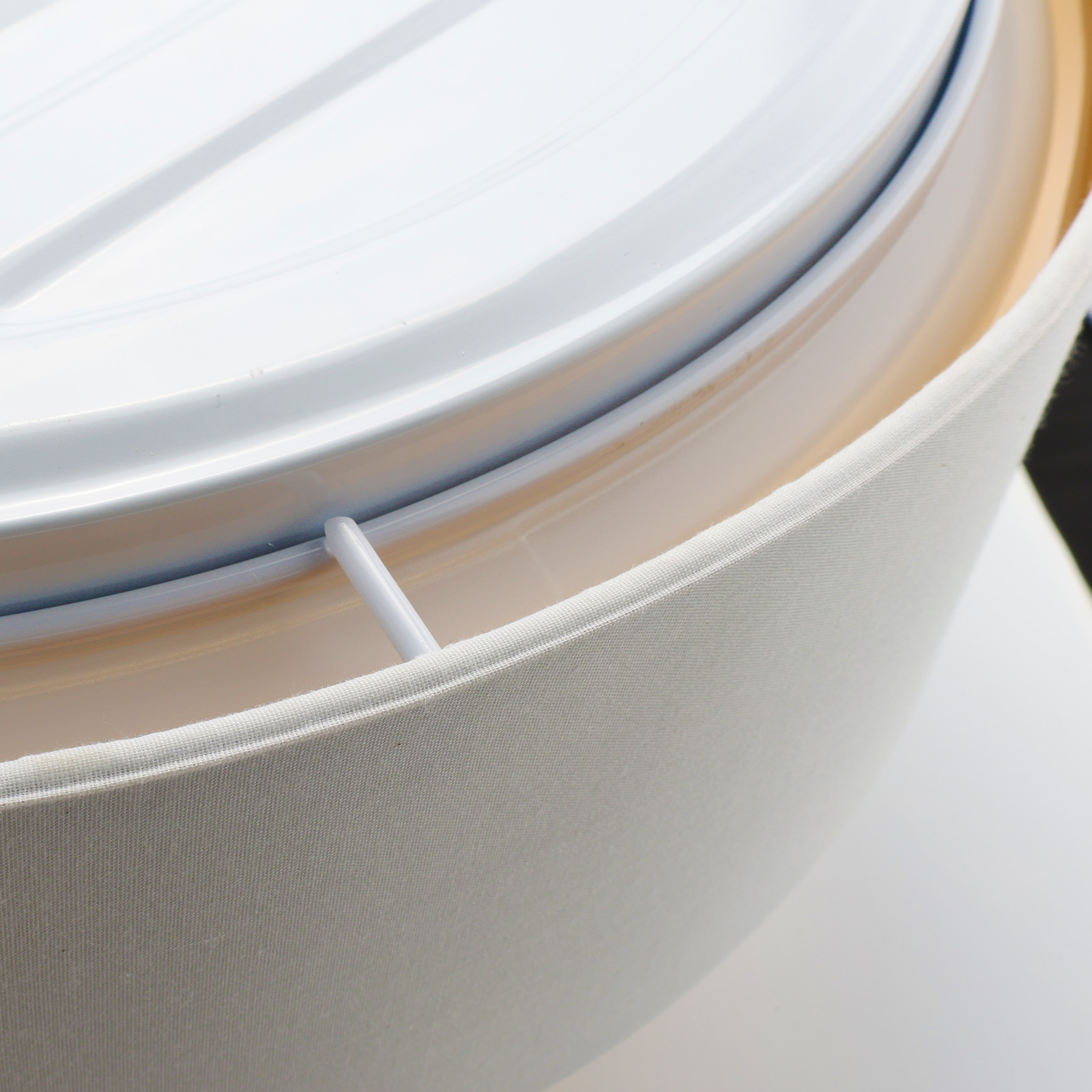 Primer plano de una lámpara de techo, interior blanco y cubierta de tela.