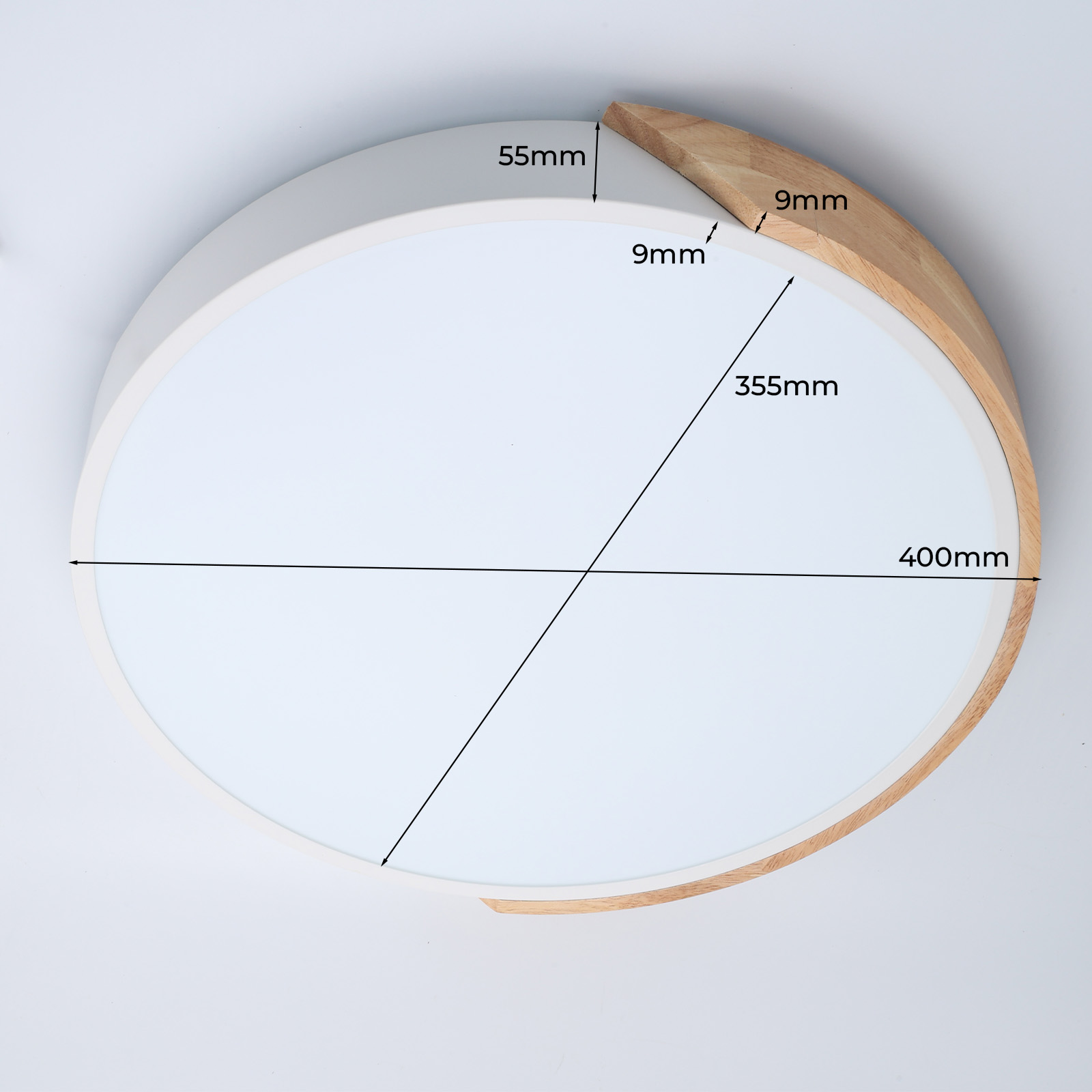 Una lámpara de techo circular blanca y con molduras de madera con anotaciones de medidas, contra una pared blanca.