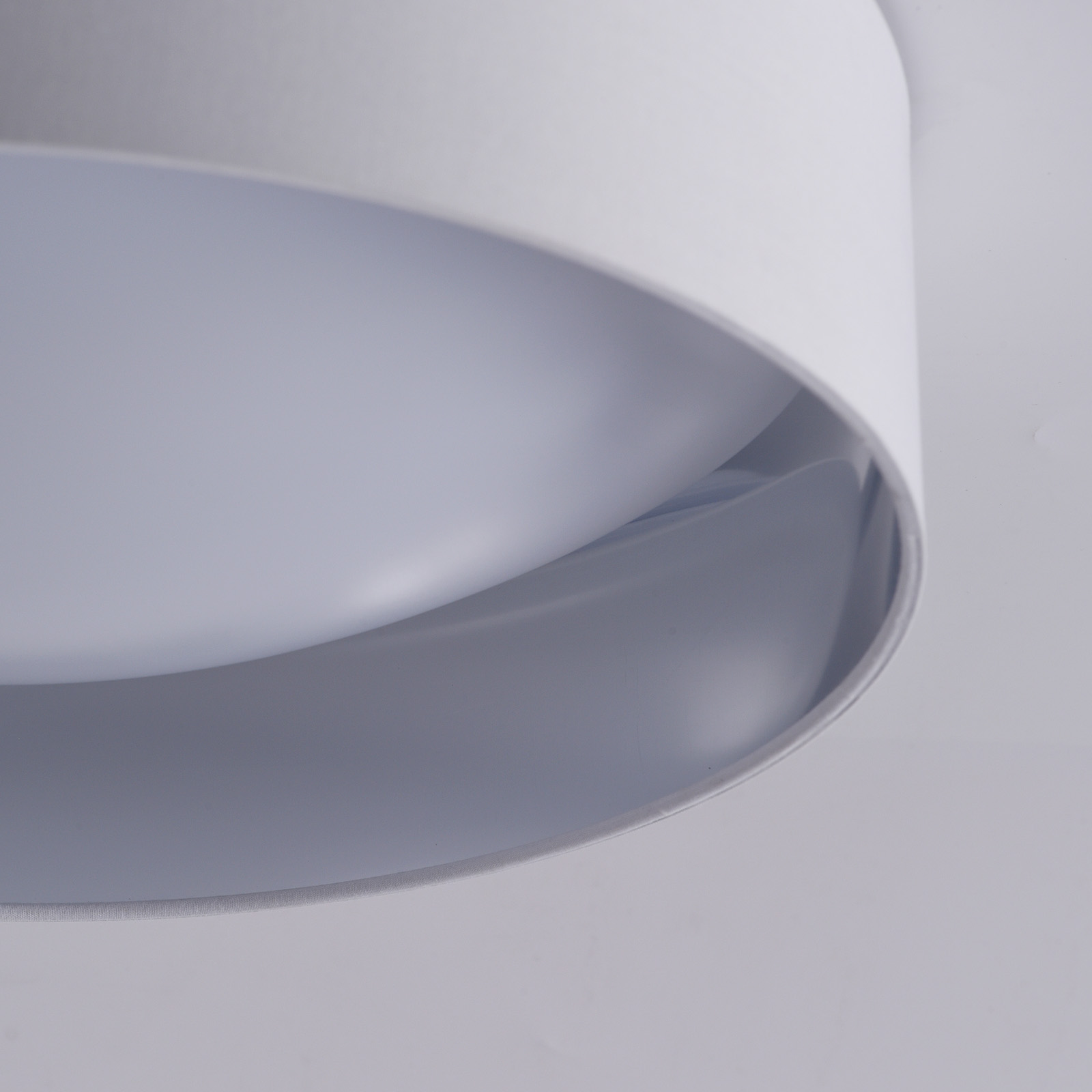 Primer plano de una lámpara de techo circular blanca. La luz parece estar encendida, y el interior es un tono más claro.