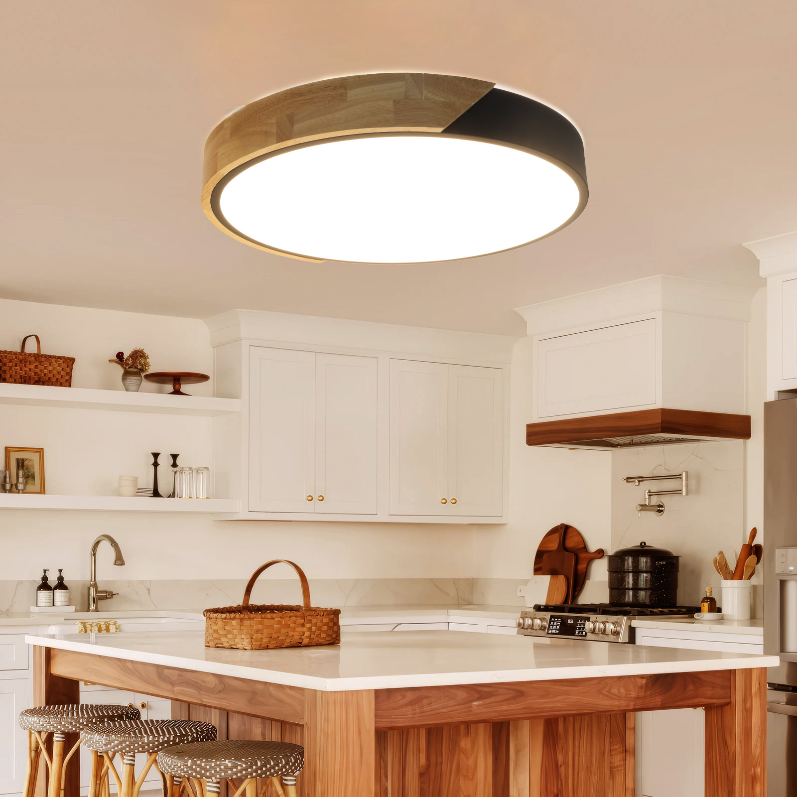 Cocina con una luz de techo redonda. Se ven gabinetes blancos, isla con taburetes, una estufa y una campana de madera.