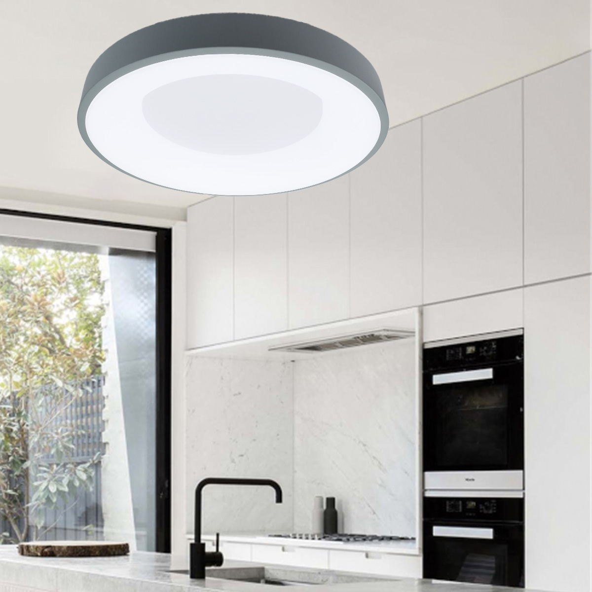 Una lámpara de techo redonda con marco gris y centro blanco iluminado, en una cocina moderna.
