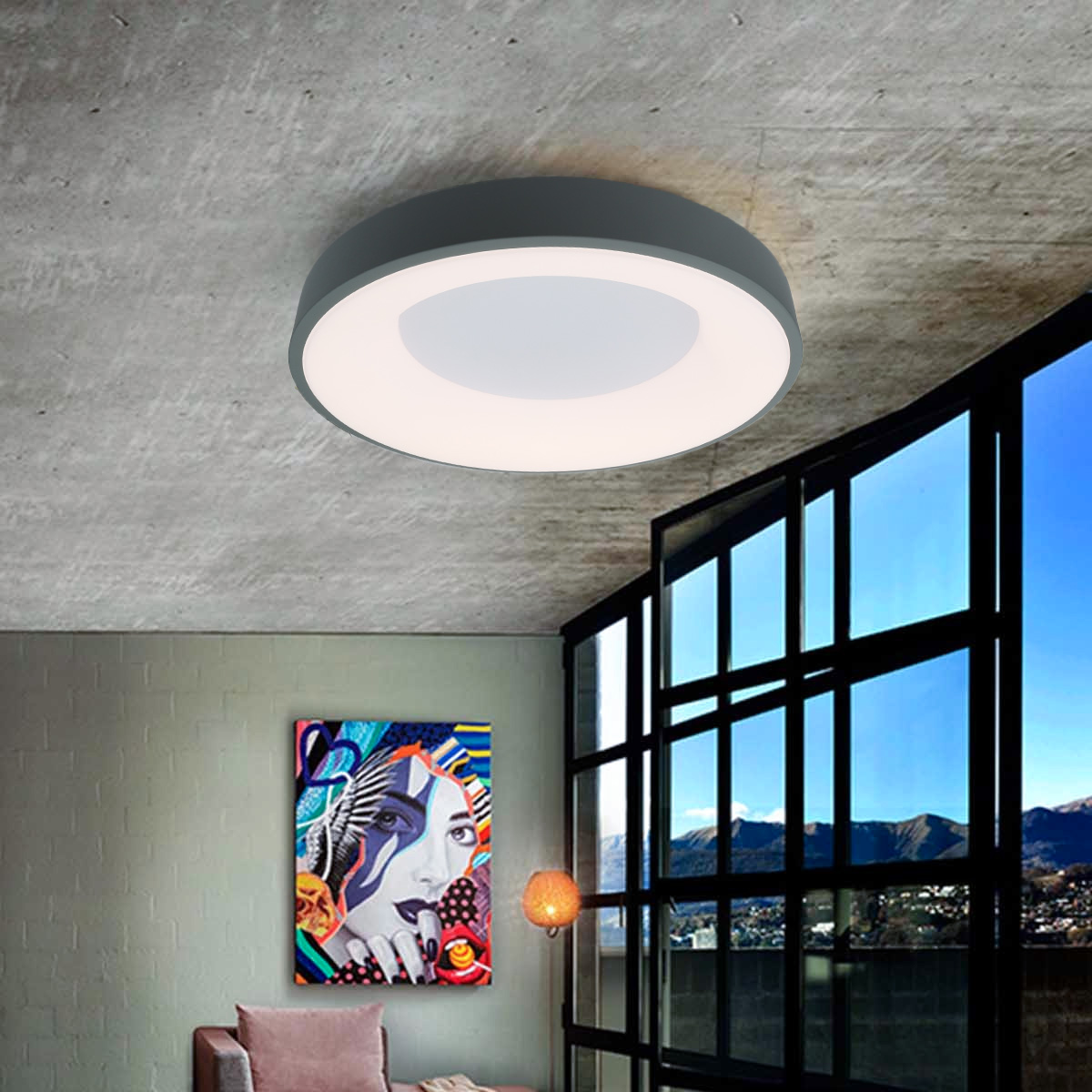 Una lámpara de techo redonda con marco gris, en una habitación con una pintura colorida y ventanas grandes.