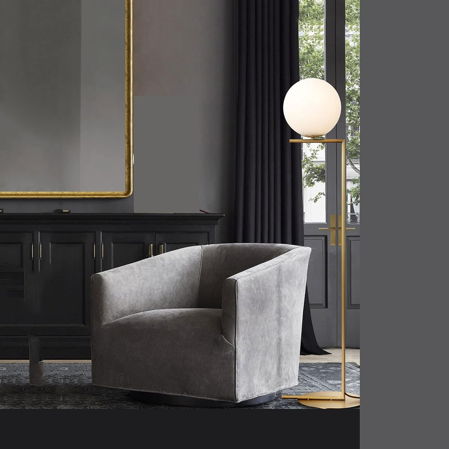 Una habitación moderna con un sillón gris, una lámpara de pie y un mueble negro.