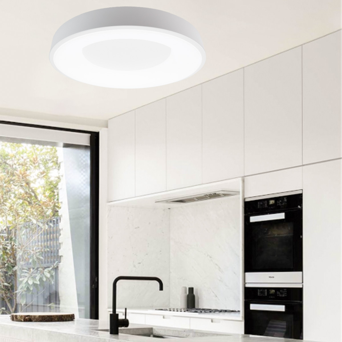 Luz de techo redonda en una cocina. Es blanca con un centro brillante. Armarios y ventana en el fondo.