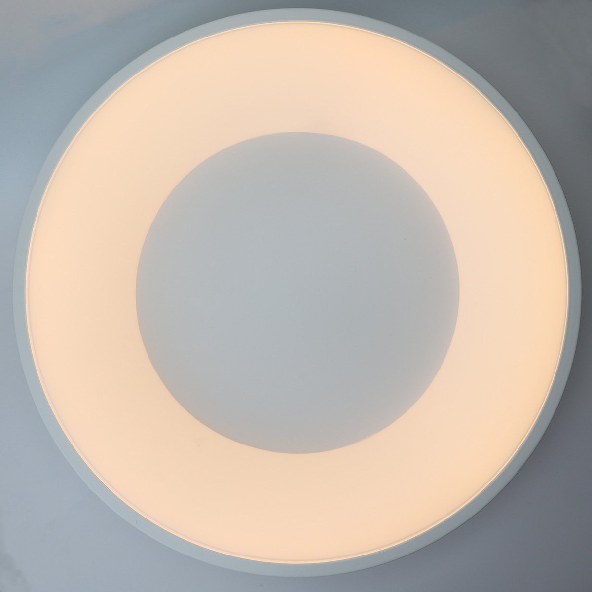 Un primer plano de una luz de techo blanca y redonda. La luz tiene un centro brillante y un anillo exterior iluminado.
