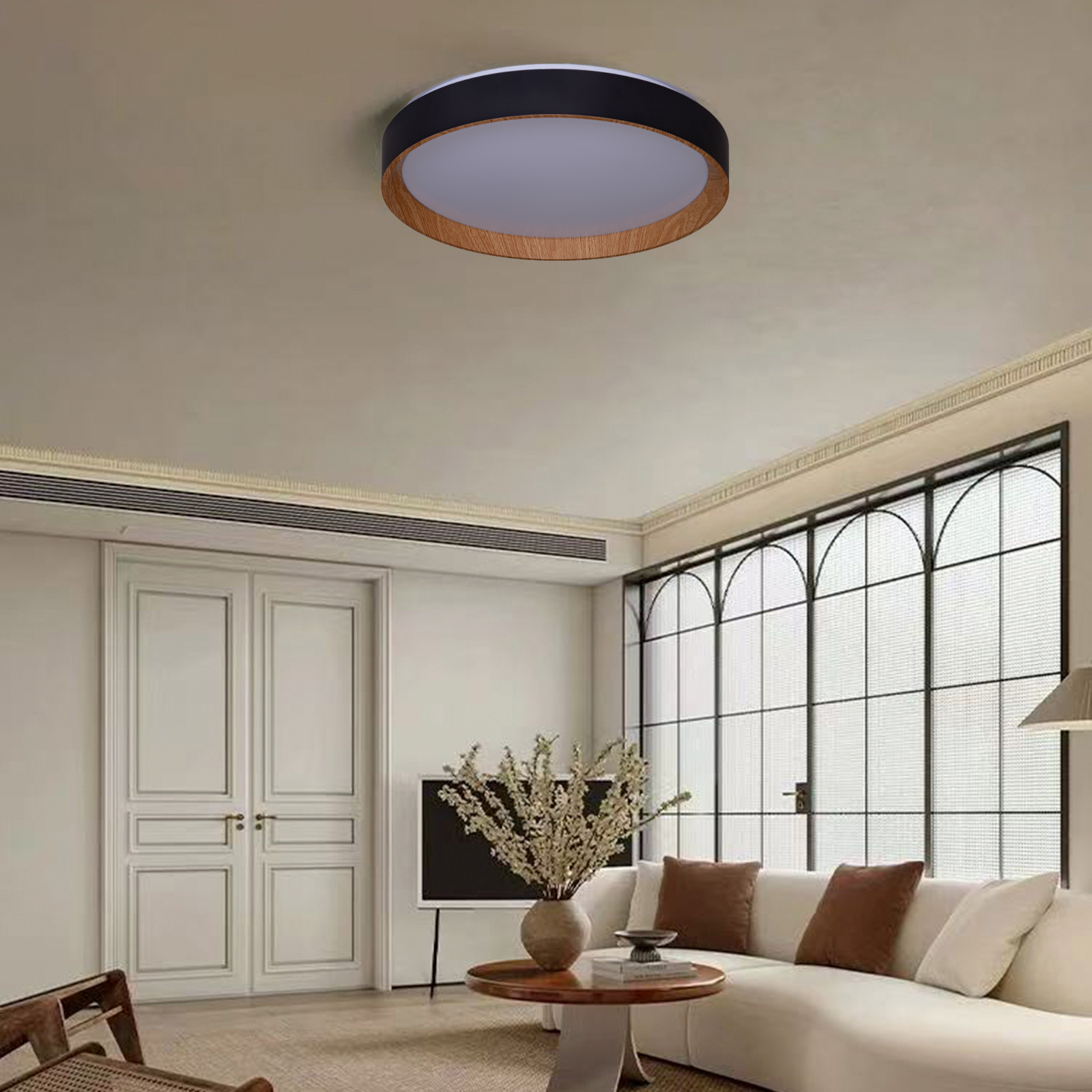 Una sala de estar con luz de techo, un sofá blanco, una mesa y una ventana grande.